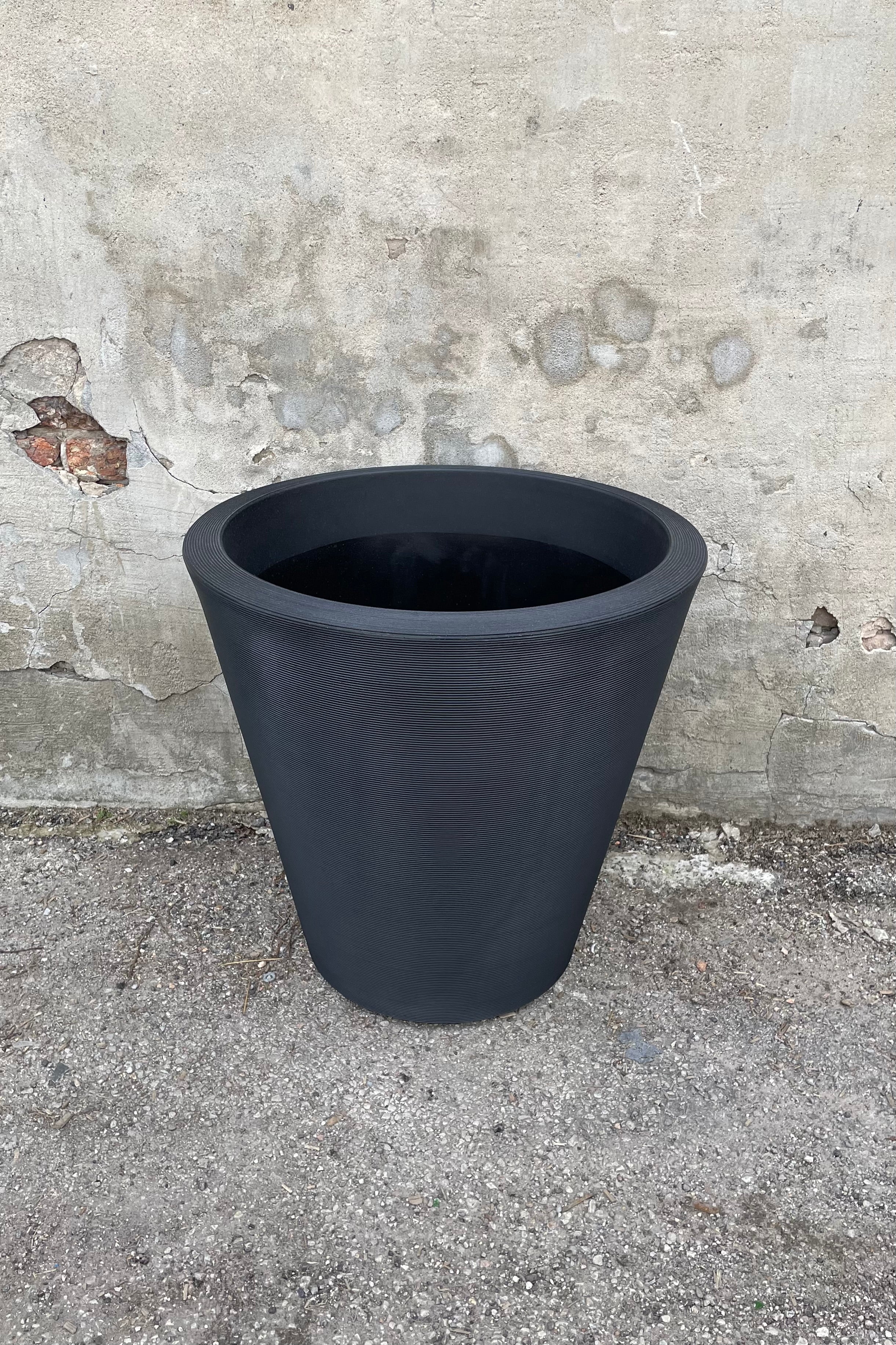 The Madison 26" container in Caviar Black against a concrete wall.,