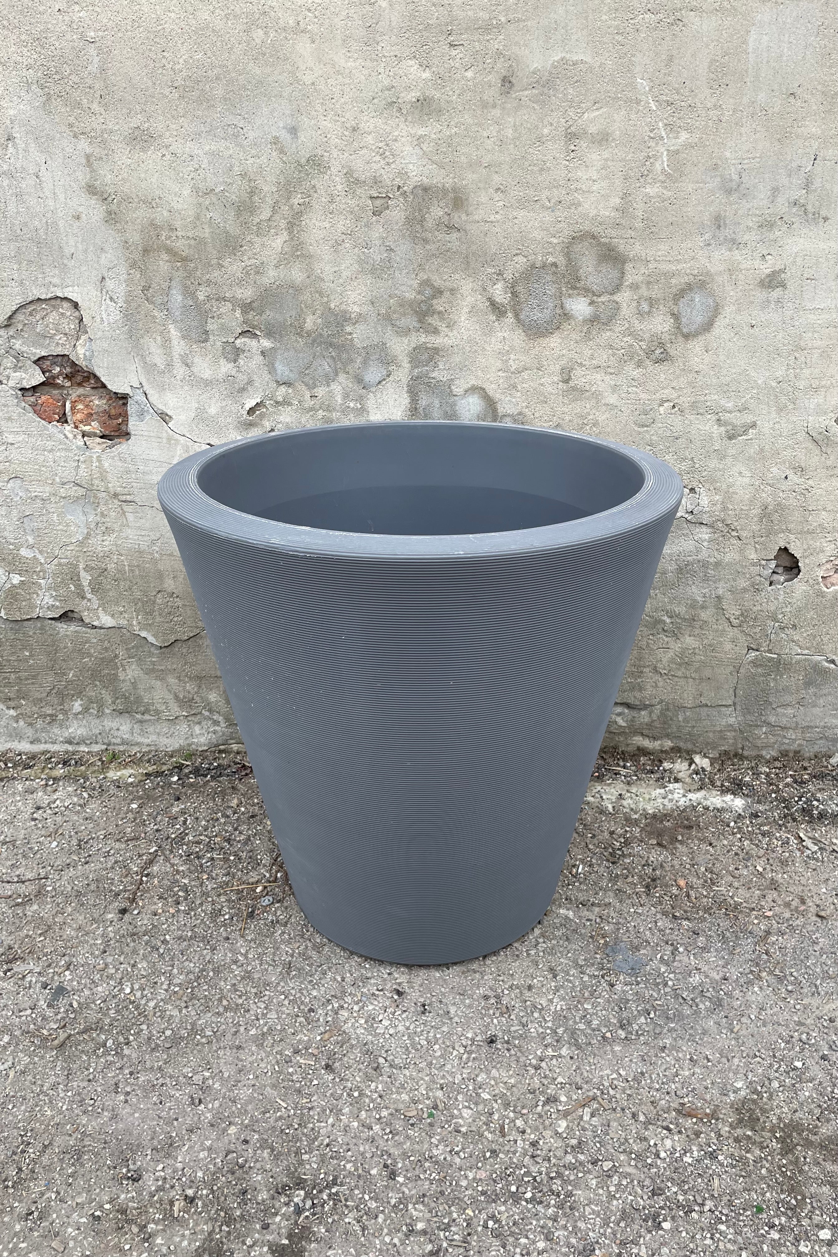 The 26" Slate Madison Slate planter against a cement wall.