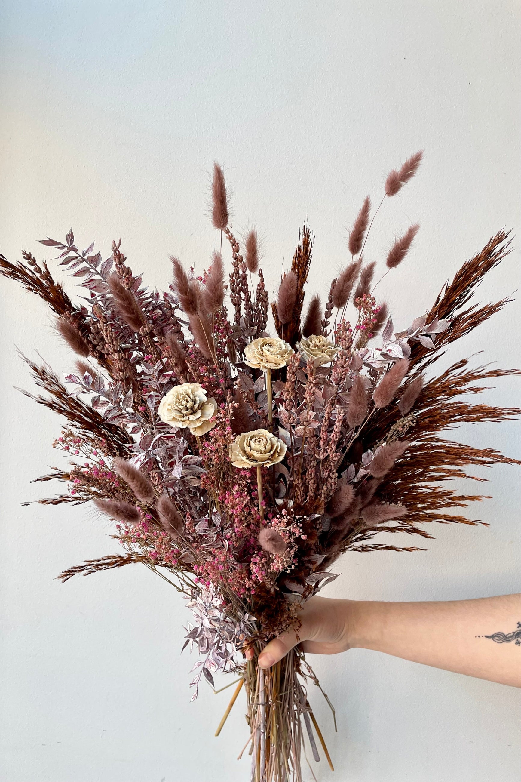 Ambrosia preserved arrangement by Sprout Home being held against a white wall. ©Sprout Home #size_$125