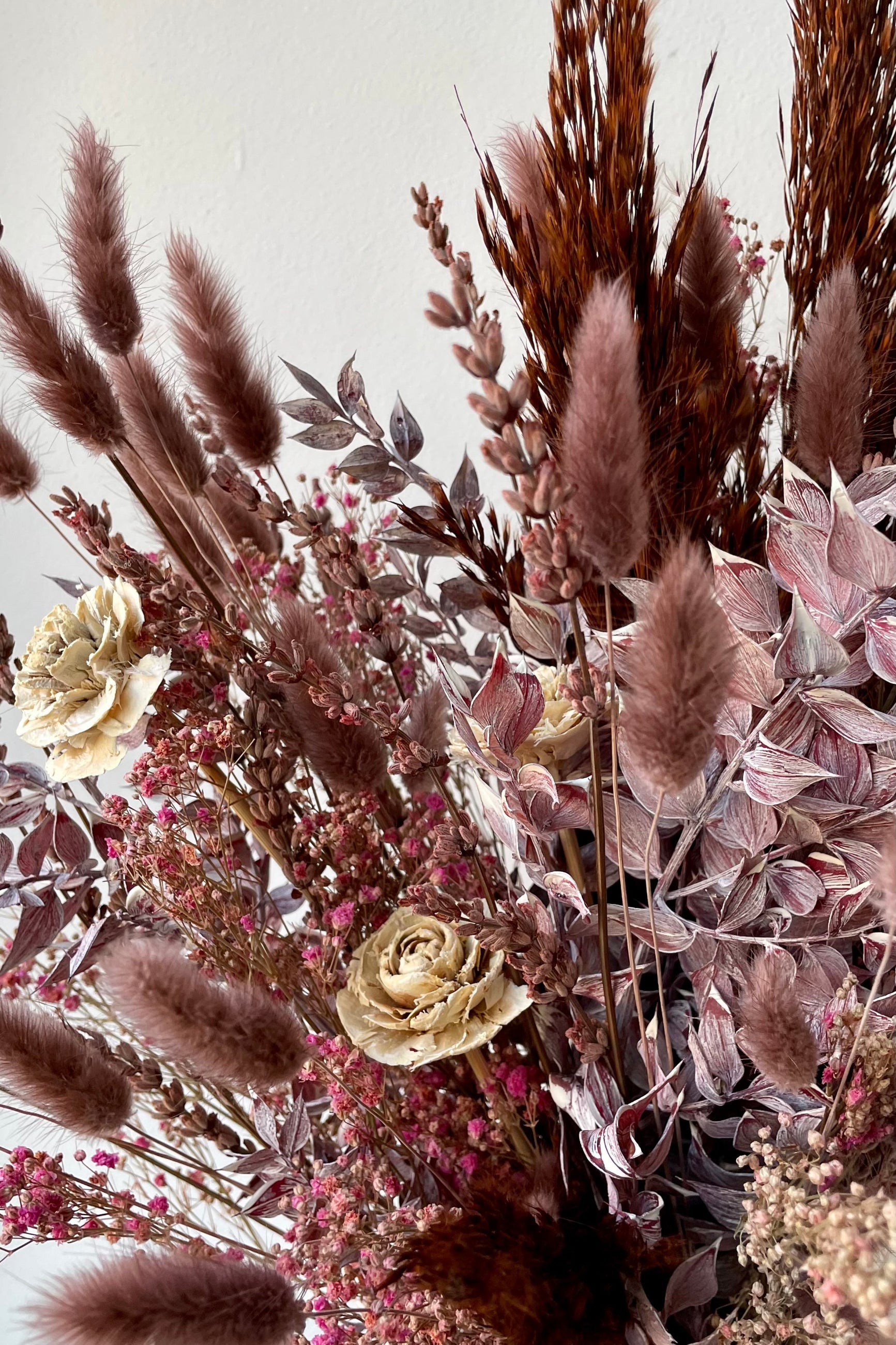 Sprout Home Ambrosia arrangement being held against a white wall showing the delicate mauve flowers. ©Sprout Home #size_$85