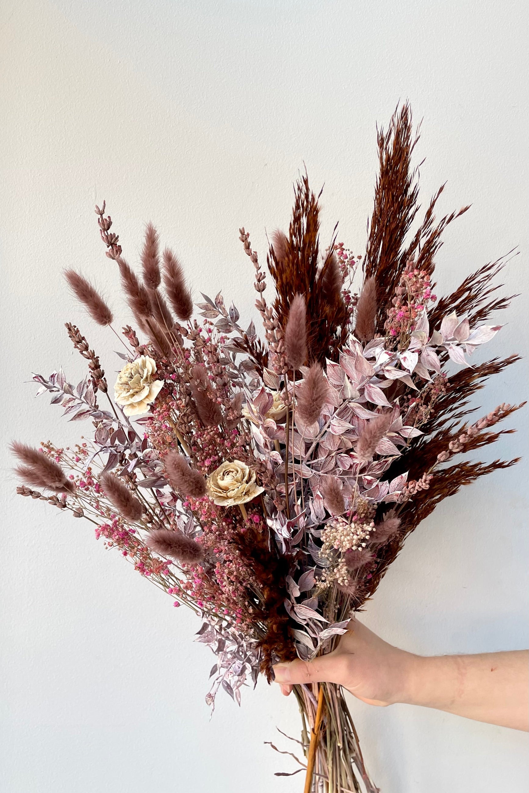 Ambrosia preserved arrangement by Sprout Home being held against a white wall. ©Sprout Home #size_$85