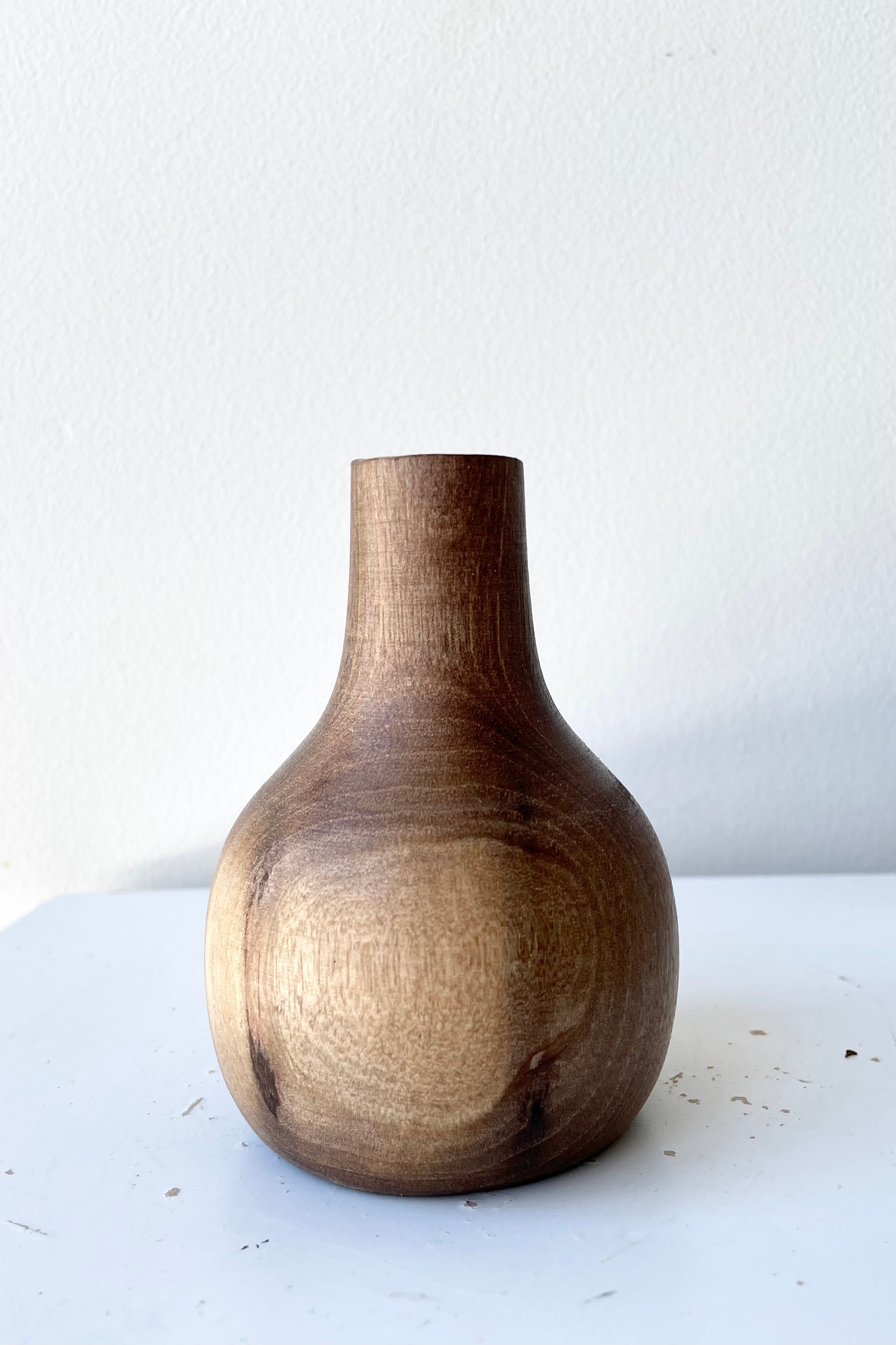The Nina walnut wood vase against a white wall with dried floral at Sprout Home.