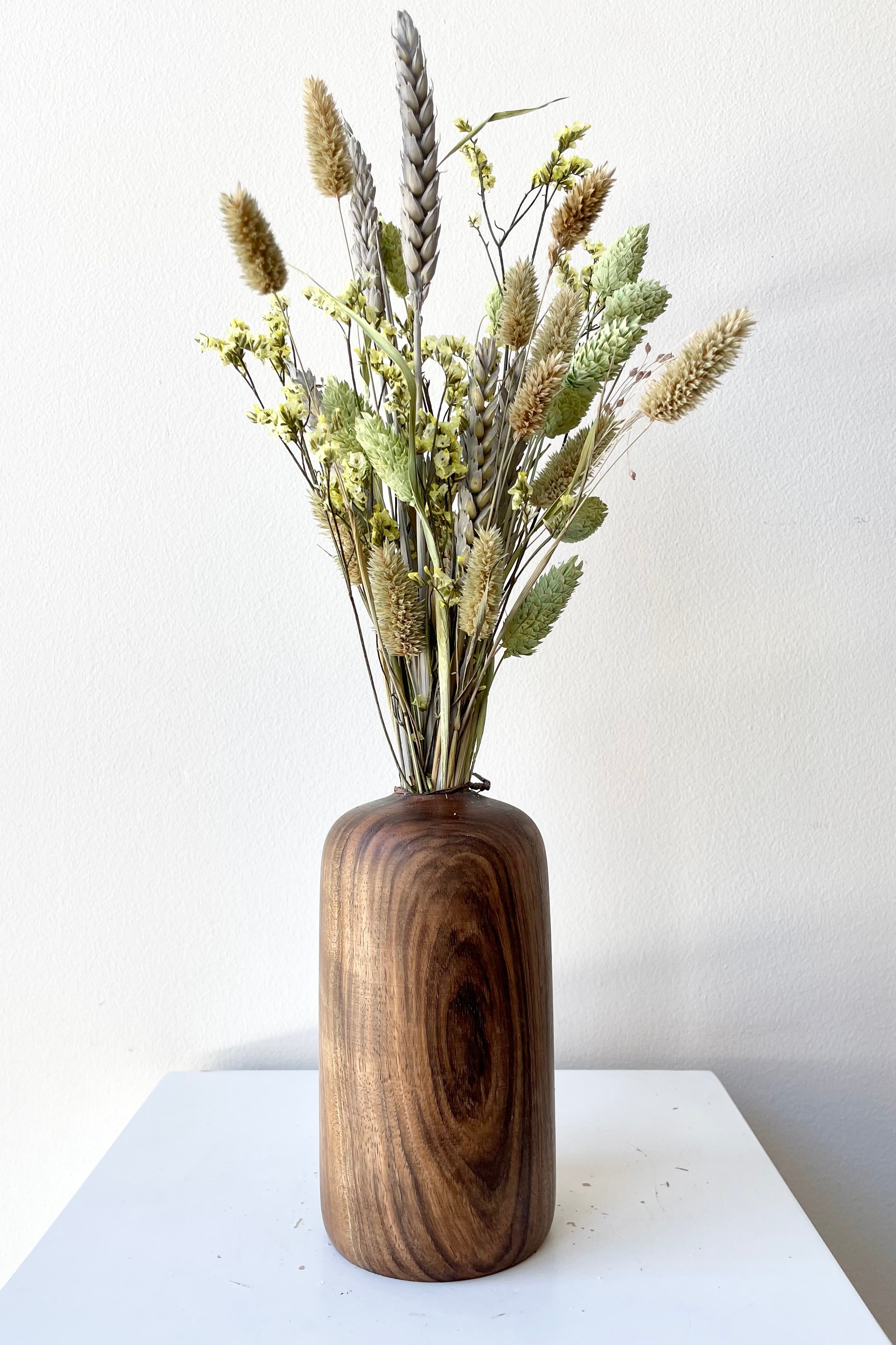 The Patti Walnut Large vase with dried floral against a white wall at Sprout Home.