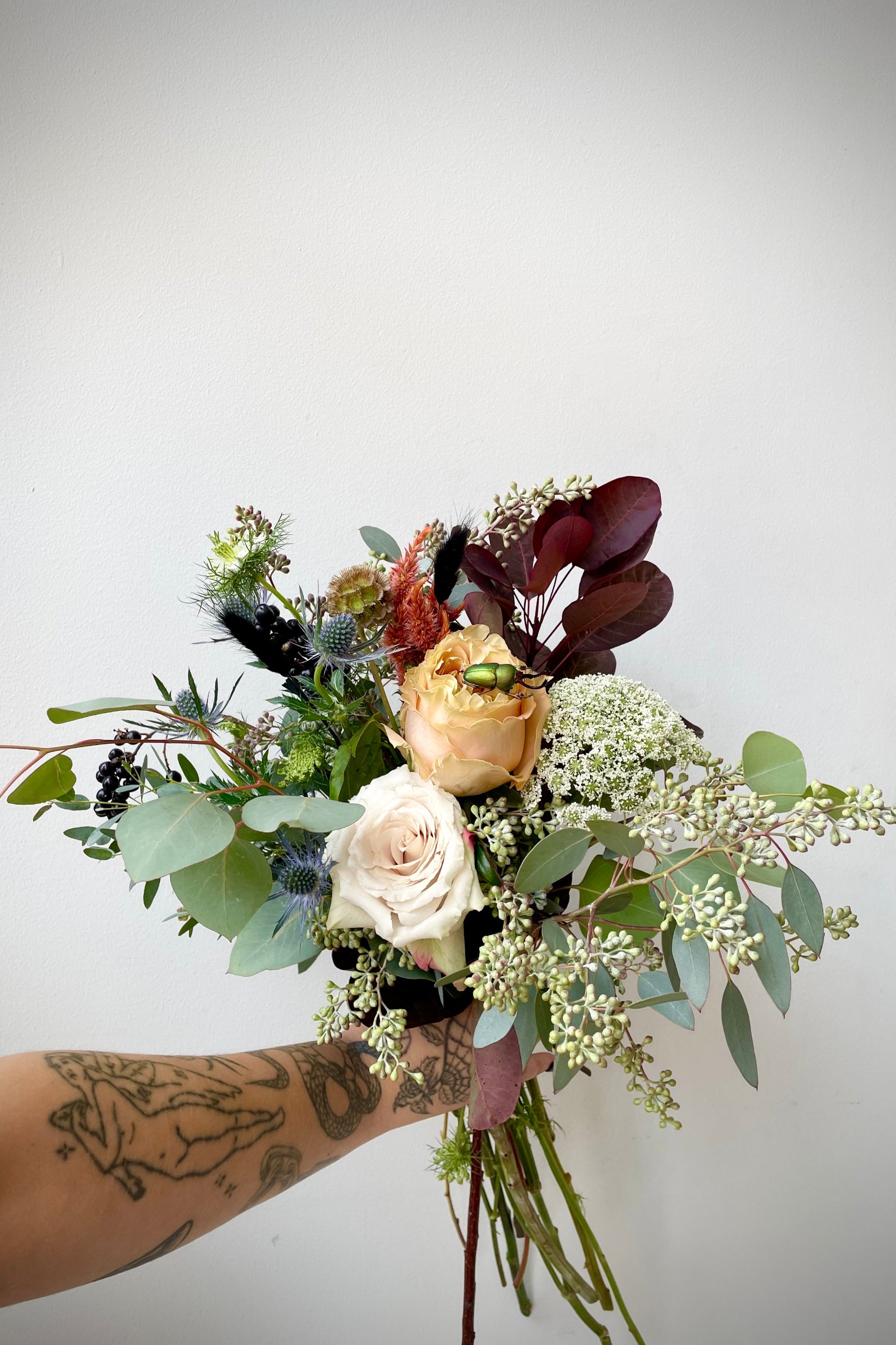 Betelgeuse arrangement with shades of gray and hints of dark foliage and white flowers with a beetle on one of the roses designed by Sprout Home. ©Sprout Home #size_$100