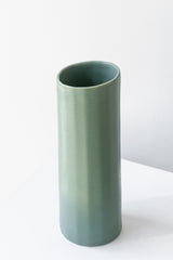 Bloom Vase in rosemary by The Bright Angle sits on a white surface in a white room.
