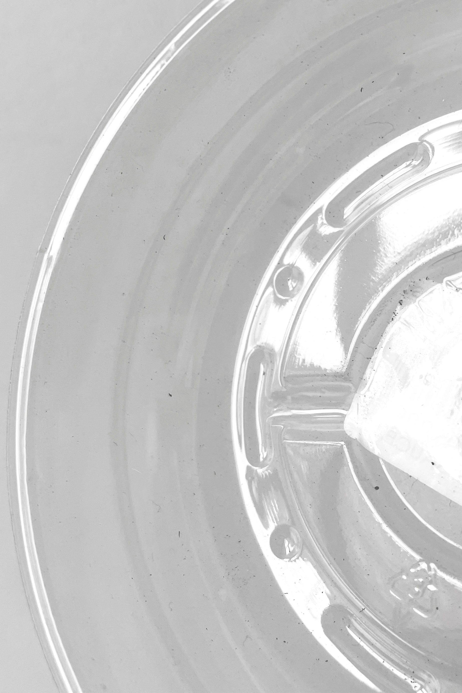 A detailed view of interior ridges on Plastic saucer 4" against white backdrop