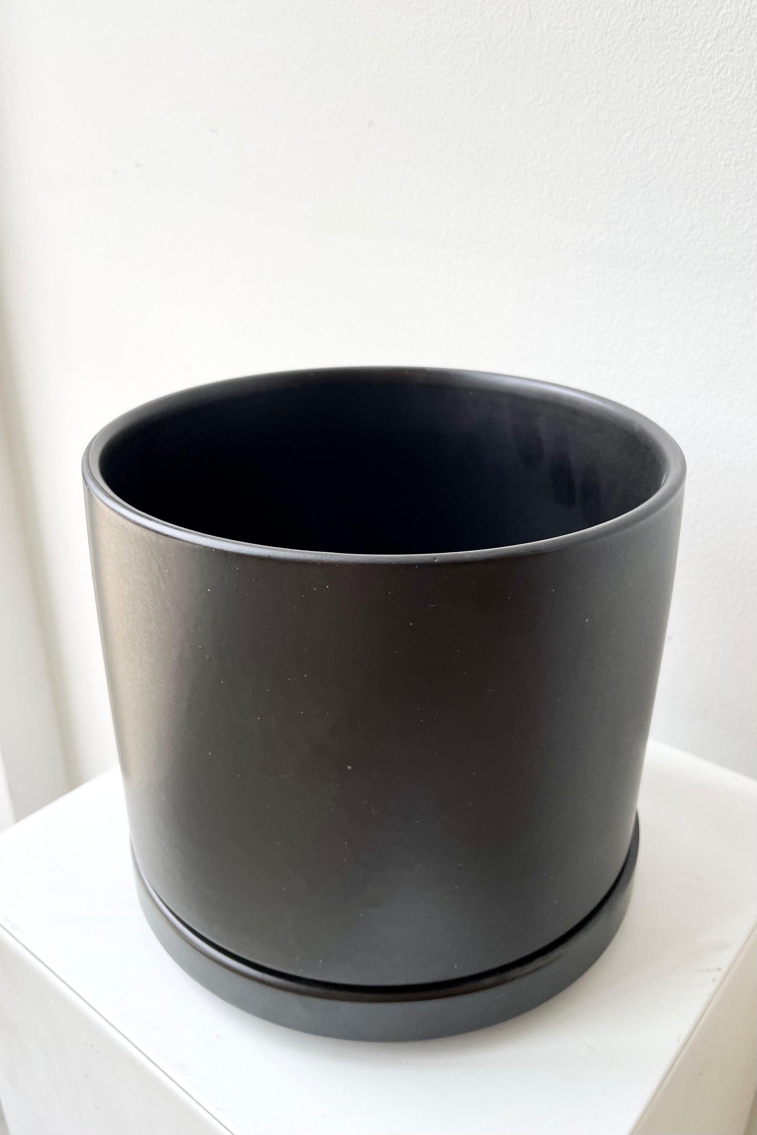 detail of the top of the Solid Cylinder & Saucer black 6” against a white wall