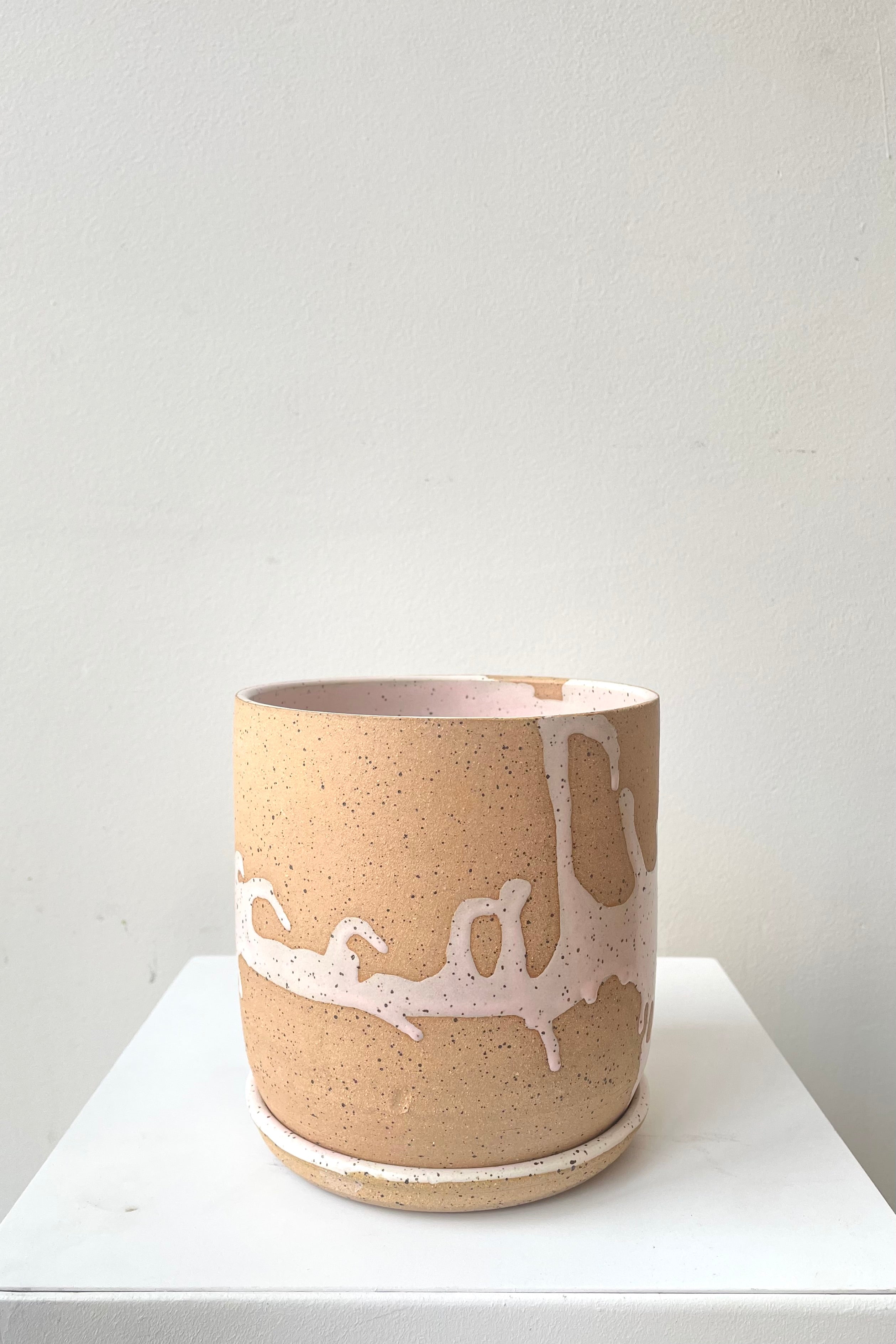 A frontal view of the 4.5" cylinder pot and saucer in pink against a white backdrop