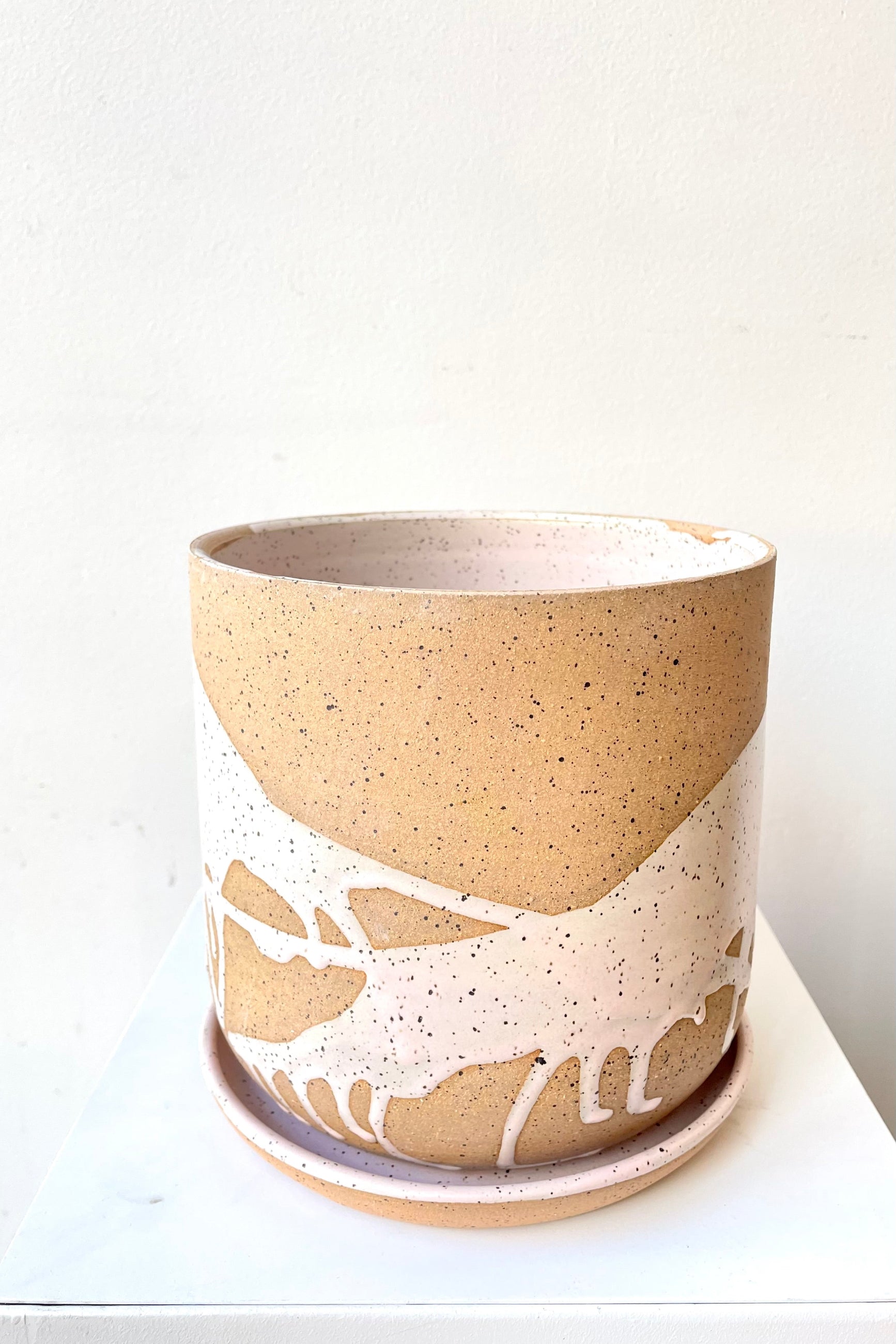 A slight over-the-lip view of the 6.5" cylinder pot and saucer in pink against a white backdrop ©Sprout Home