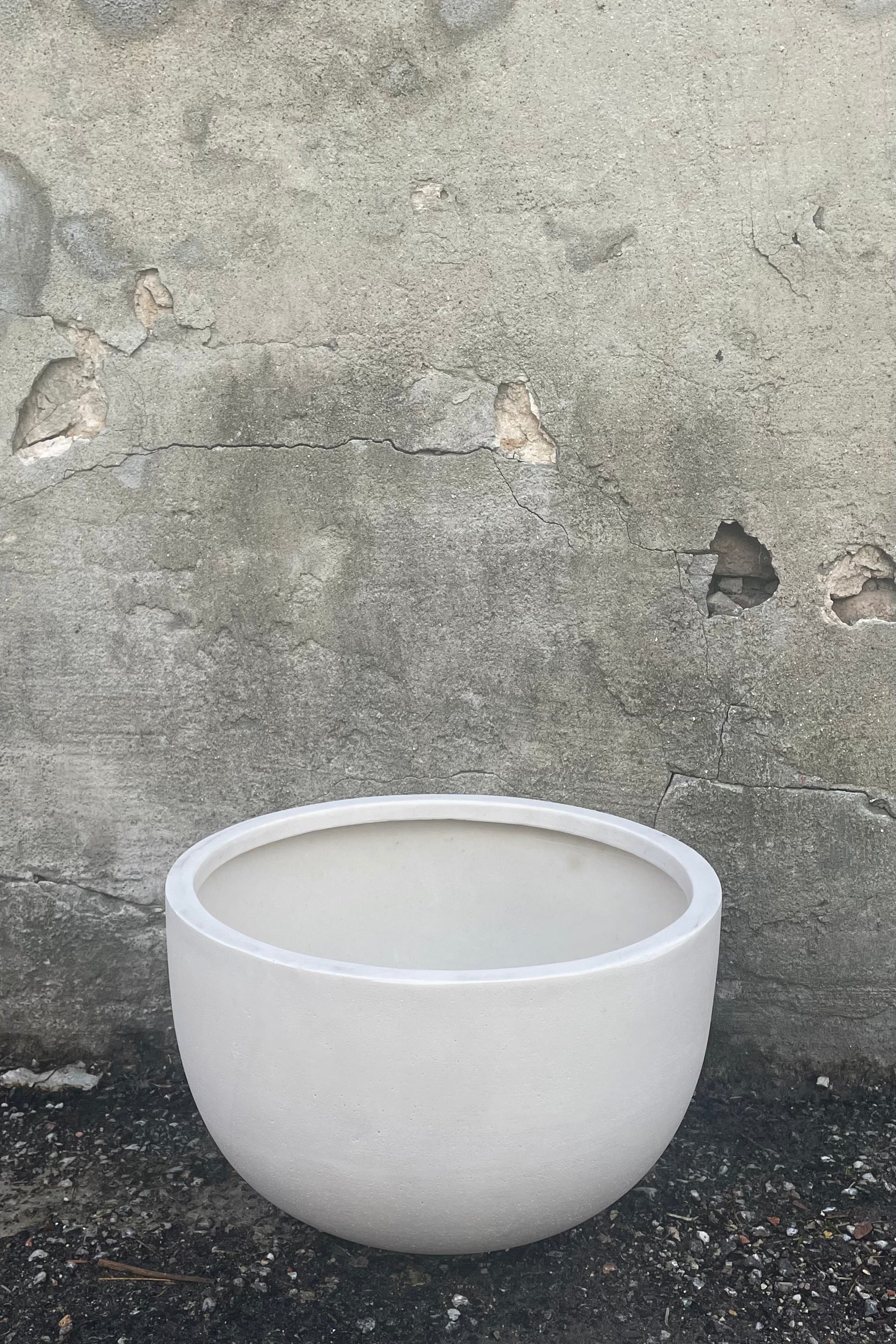 A frontal view of Sunny Bowl Natural White Medium against a concrete backdrop
