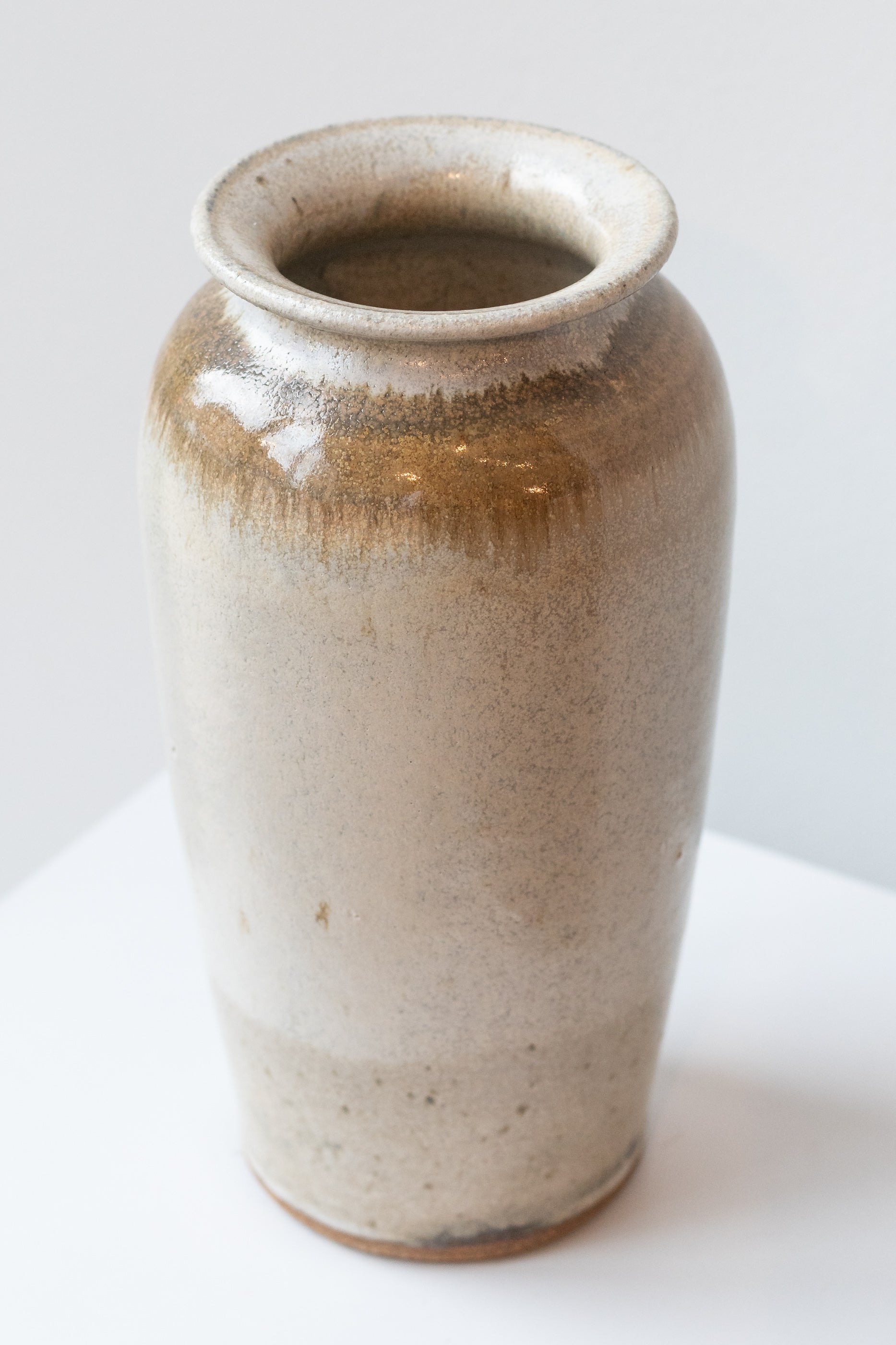 Bruning Pottery ivory and iron glazed tall ceramic vase in front of white background