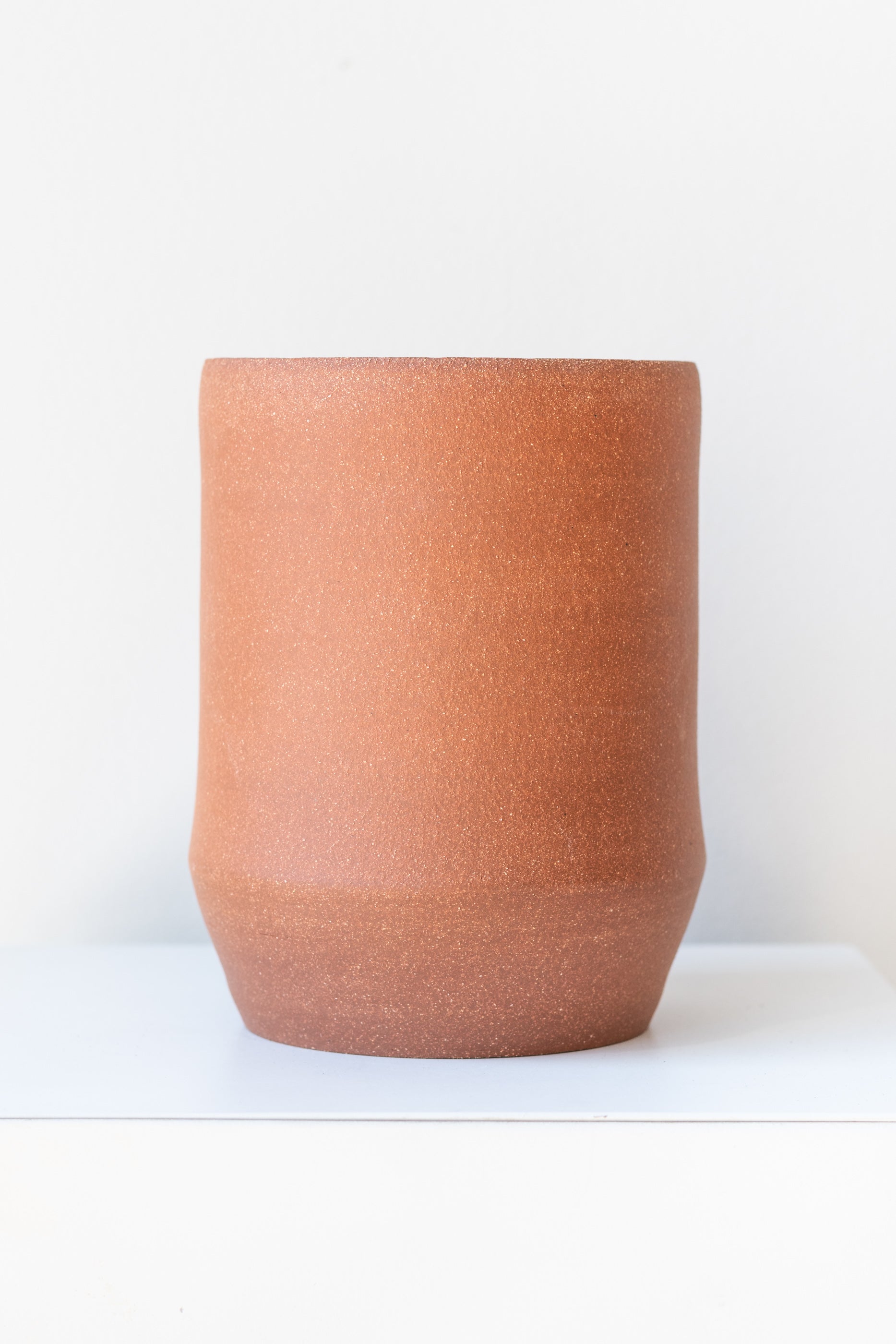Megan Suave Ceramics large brick stoneware vase on a white surface in a white room