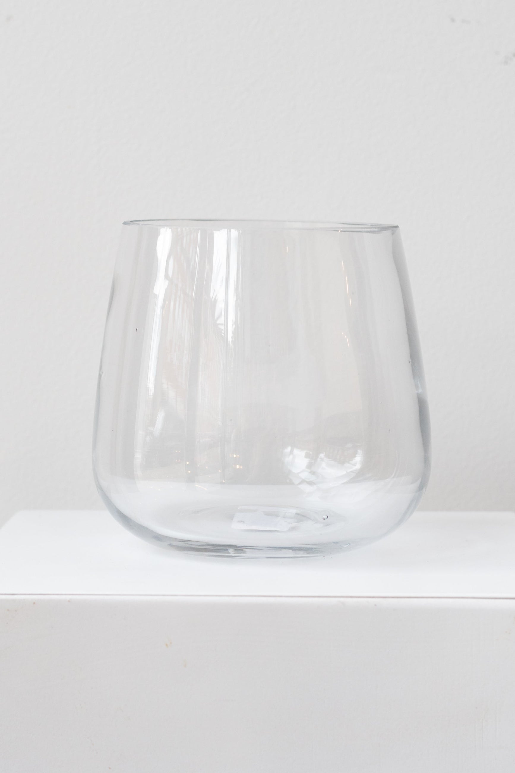 A clear glass vase with a round bottom and a reverse taper shape, displayed against a white background. ©Sprout Home