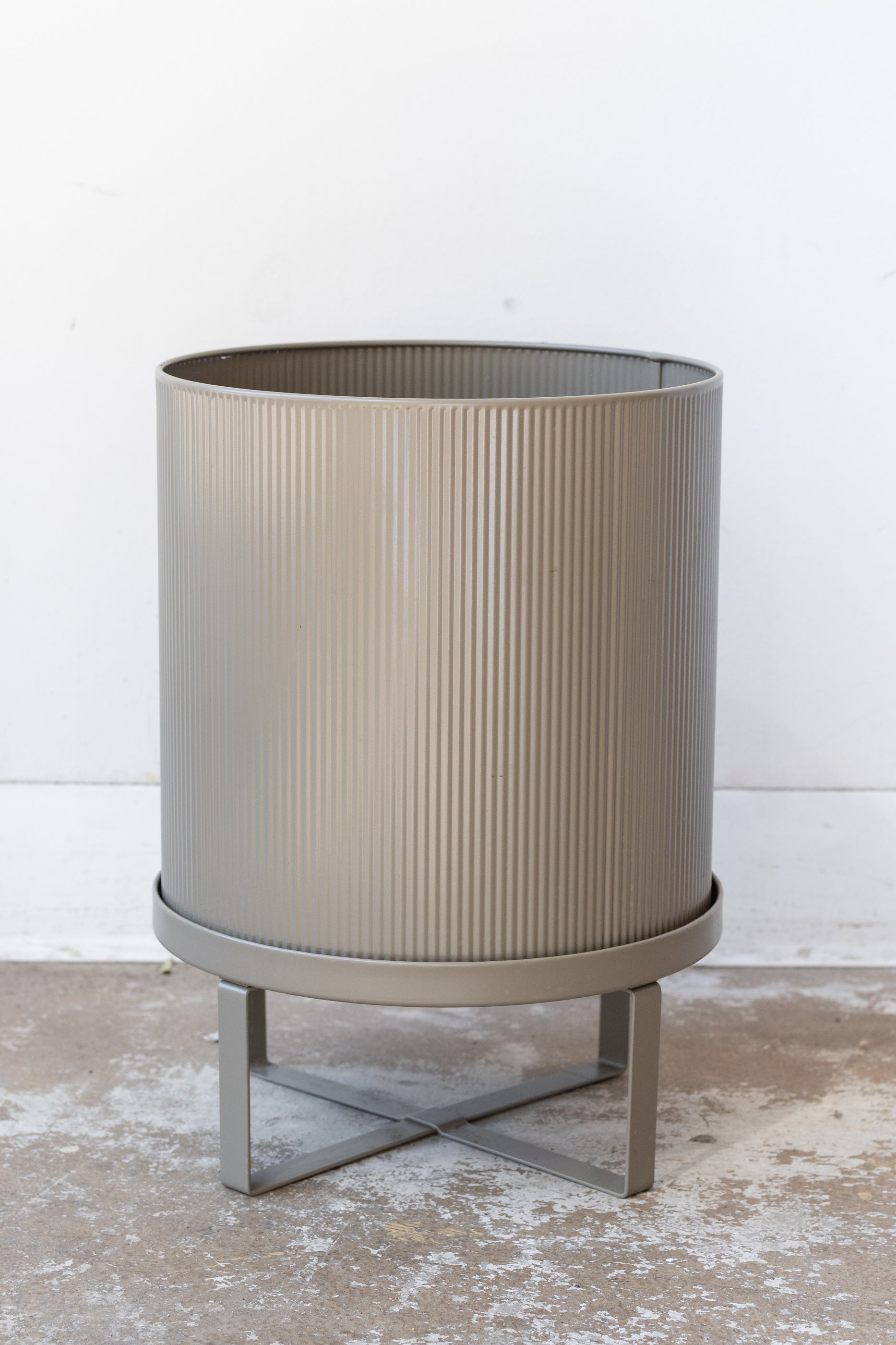 Large warm grey Bau Pot by Ferm Living on a concrete floor in front of white background