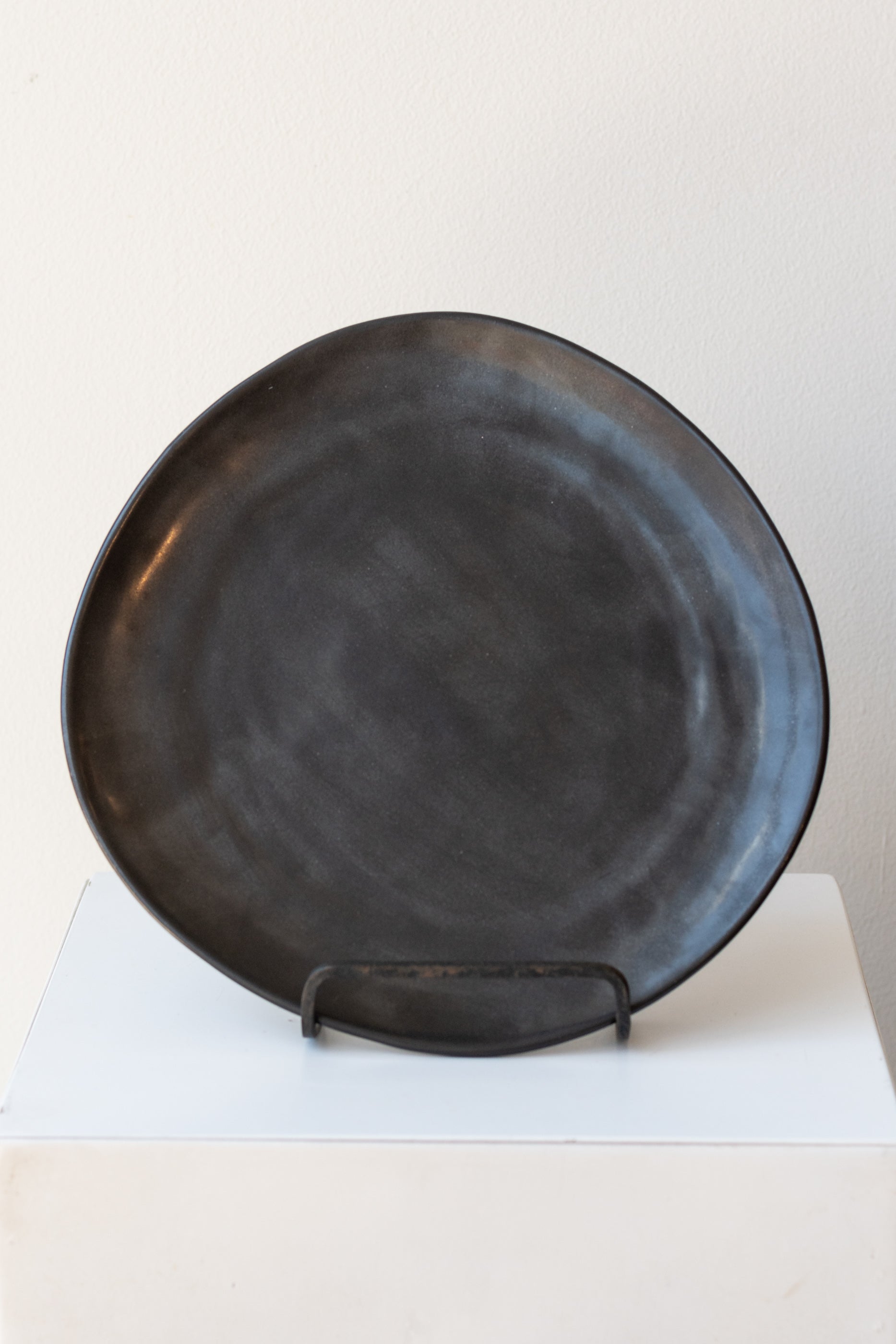 Ferm Living Flow Plate black medium on iron stand in front of white background