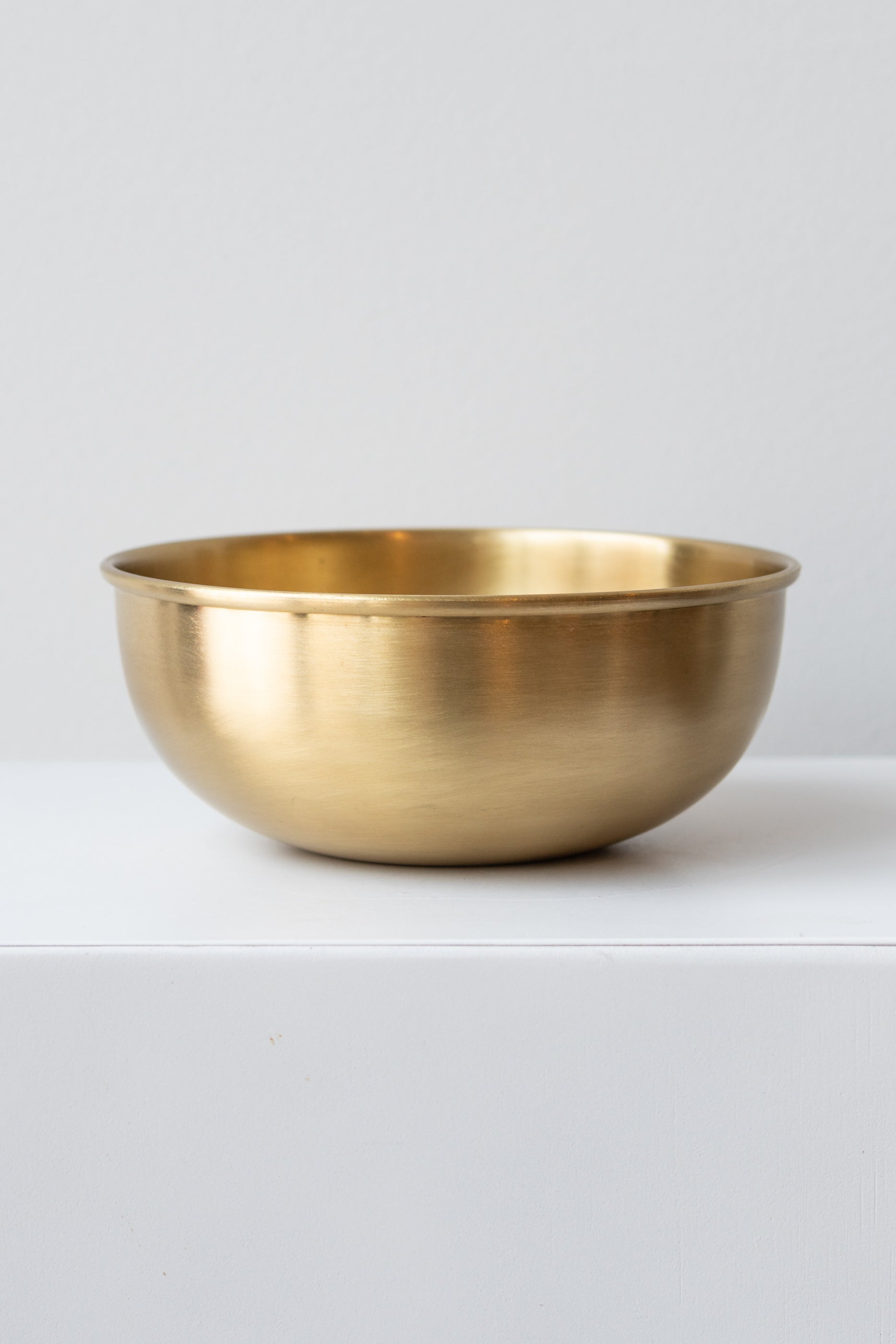 Extra Large brass bowl by Fog Linen Work sits on white surface in a white room