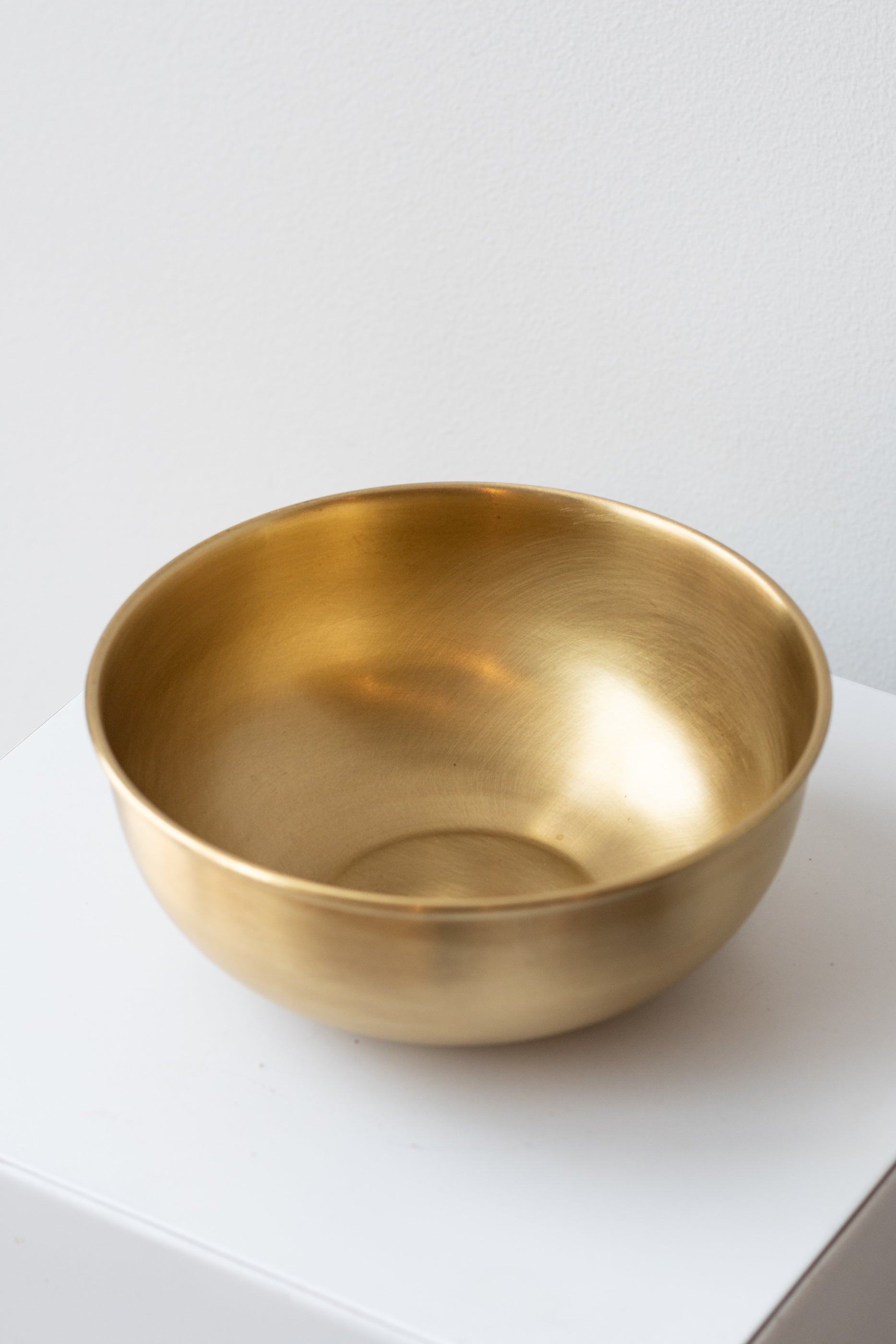 Extra Large brass bowl by Fog Linen Work sits on white surface in a white room