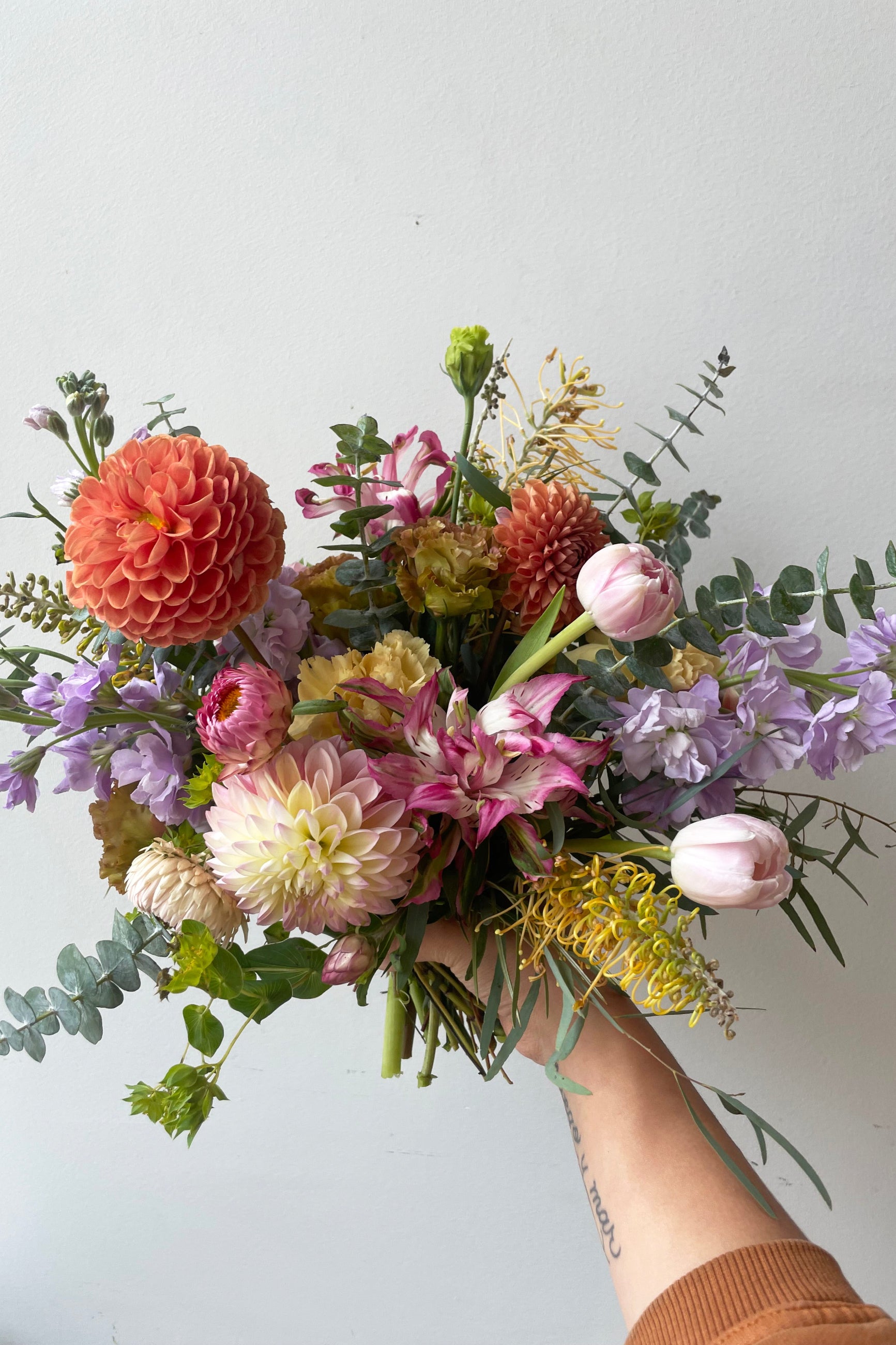 A hand holds fresh Floral Arrangement Dawn with dahlias and tulips from Sprout Home Floral ©Sprout Home #size_$100