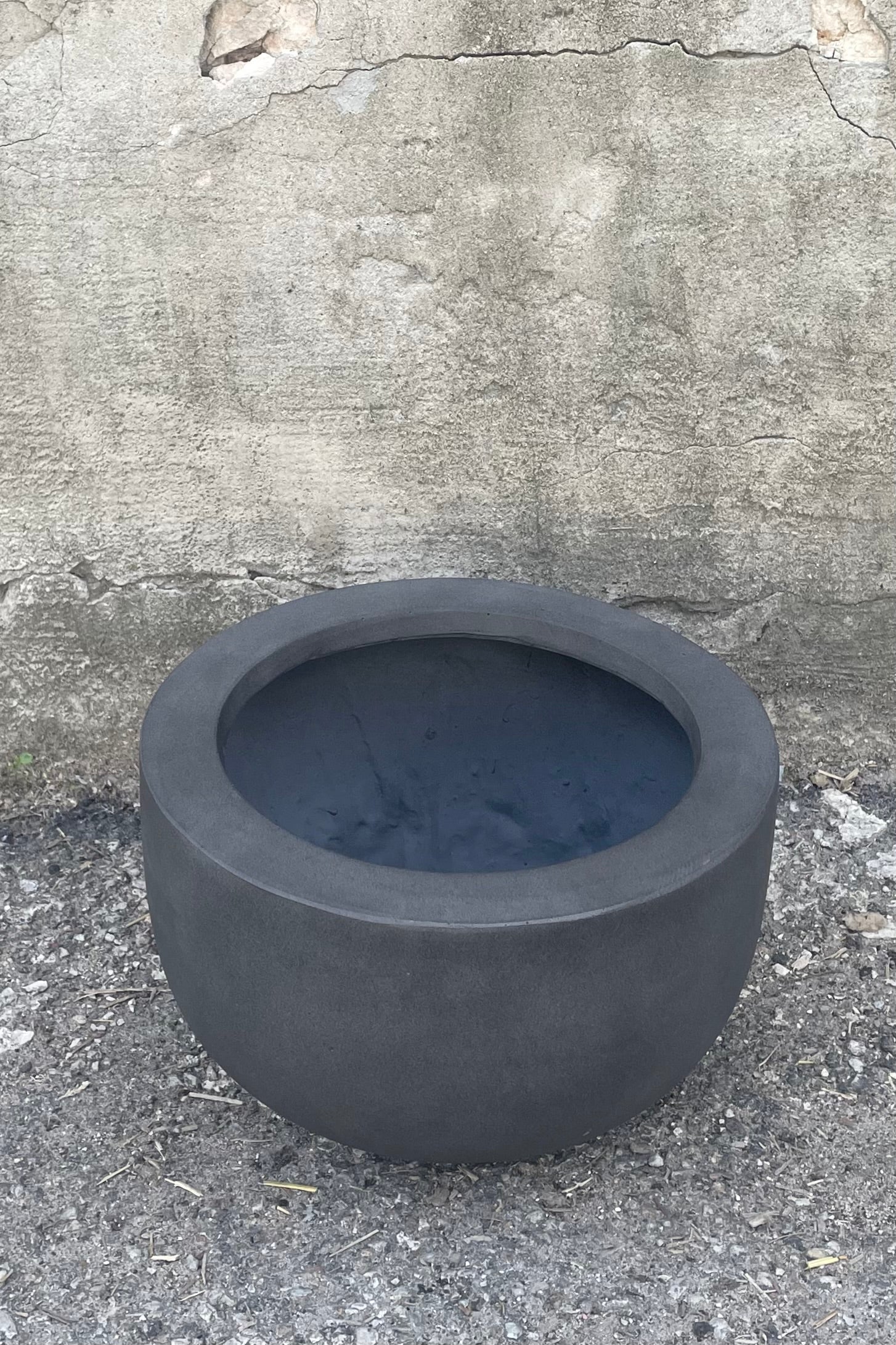 A slight overhead view of Sunny Fiberstone Pot Grey Medium against concrete backdrop