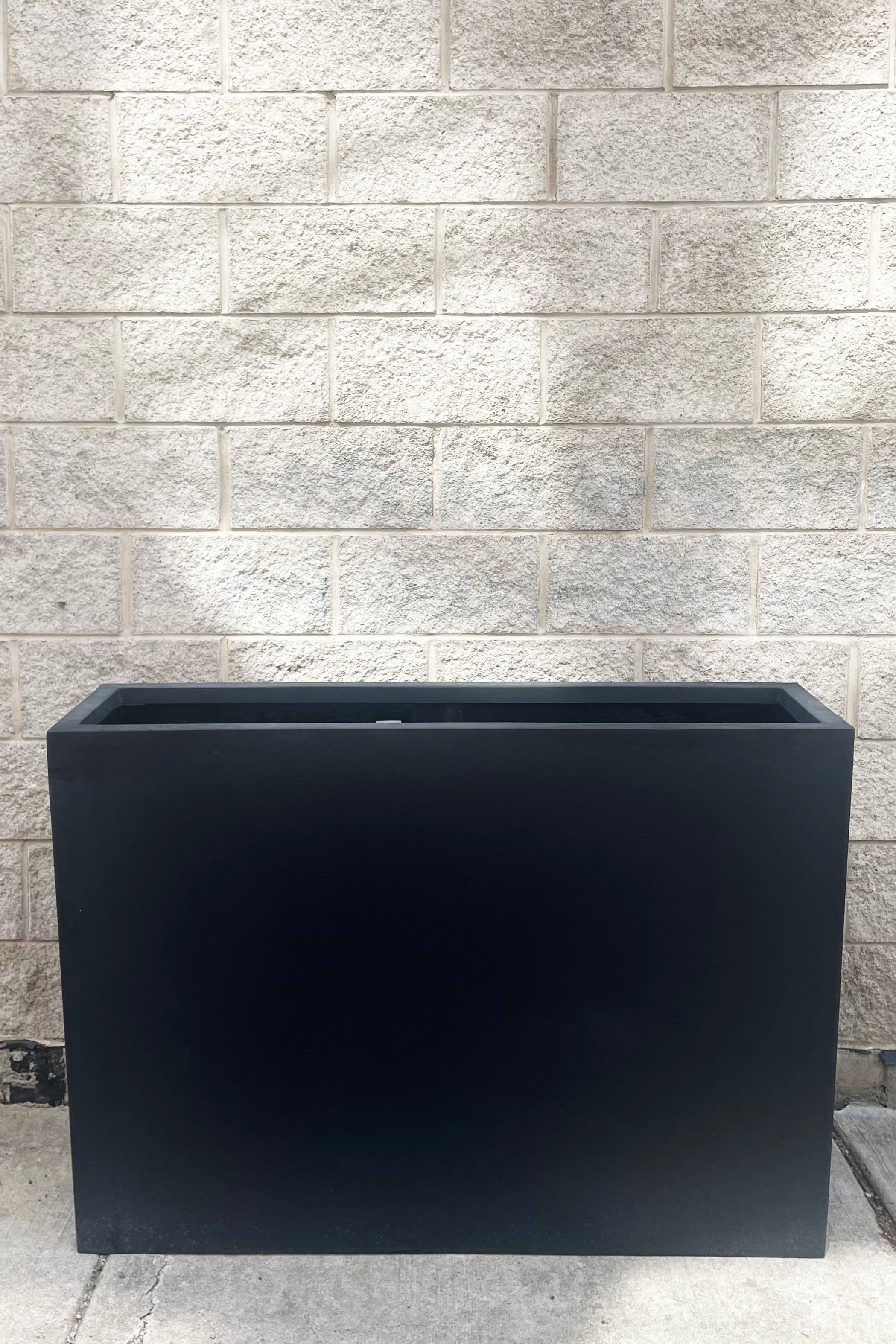 A full frontal view of Jort Slim Fiberstone Planter black large against concrete backdrop