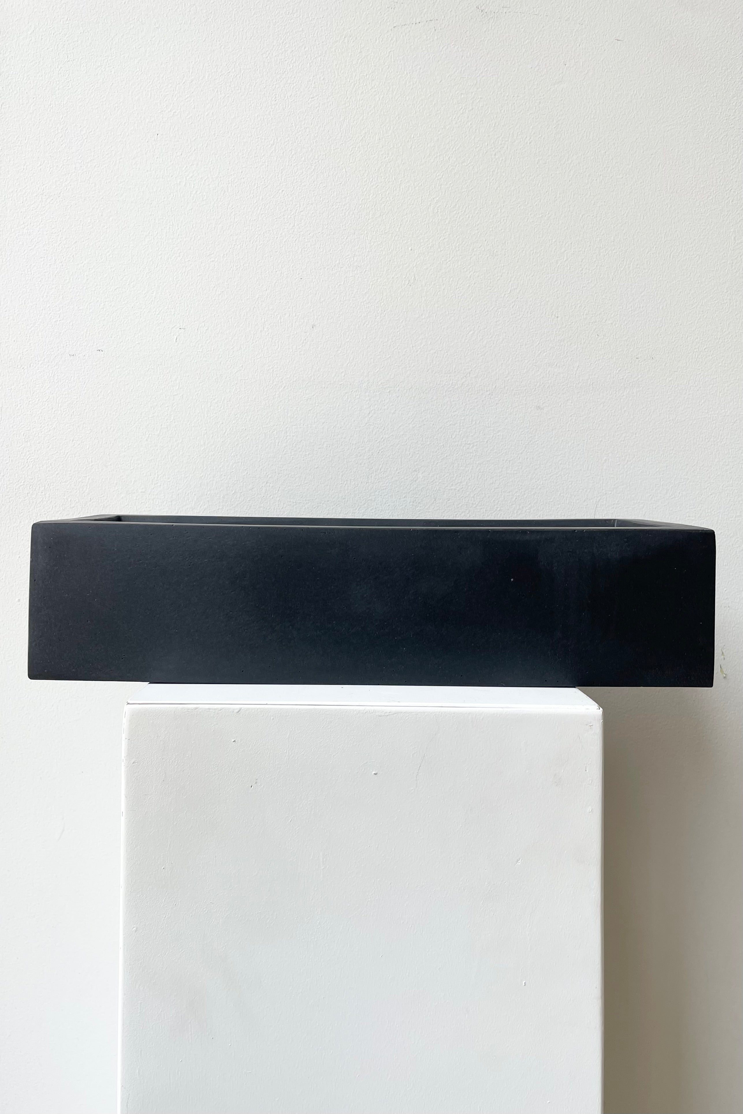 Balcony Planter Slim Low Black Extra Small against a white wall