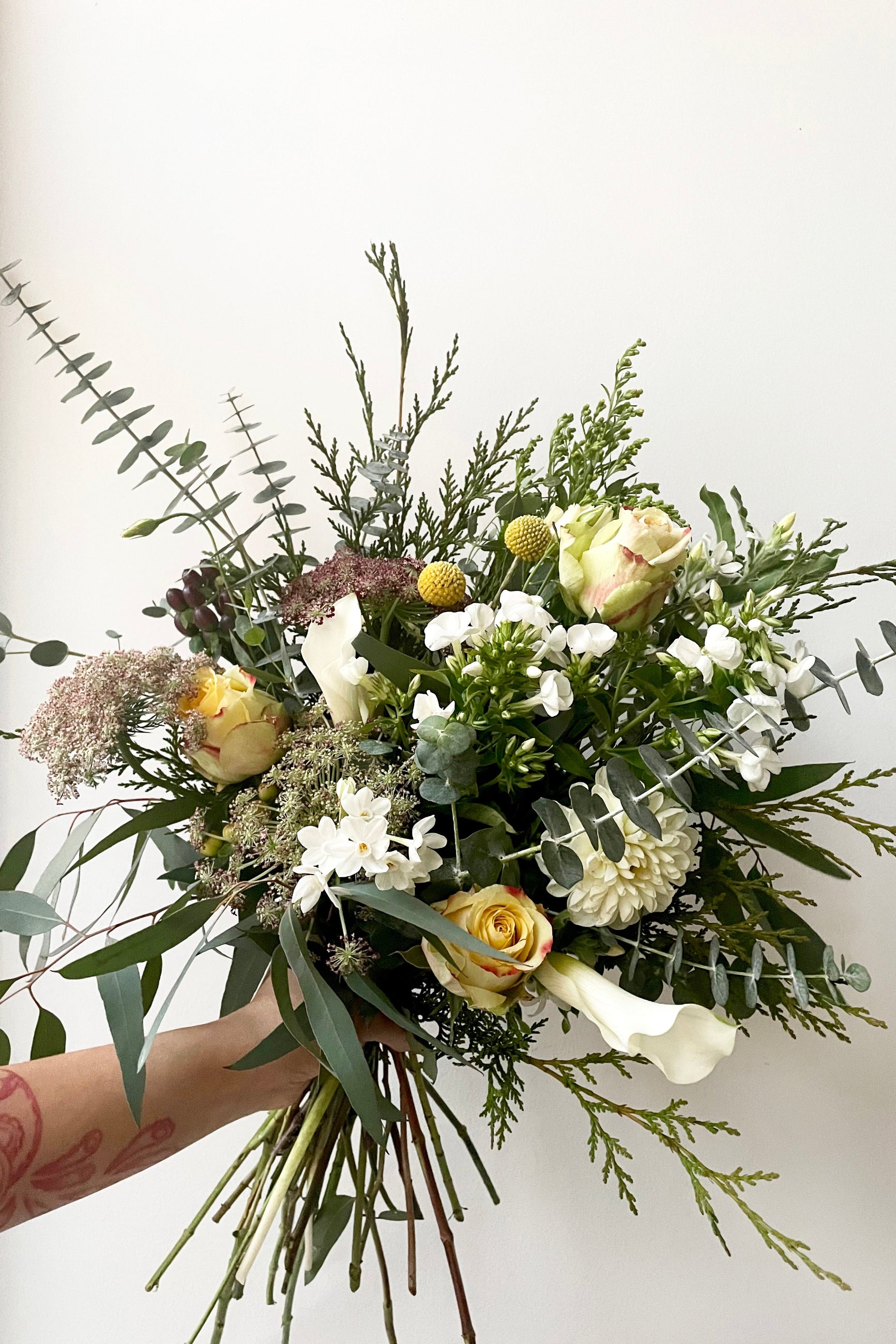 A hand holds an example of fresh Floral Arrangement Eggnog with white paperwhite from Sprout Home Floral in Chicago ©Sprout Home #size_$130