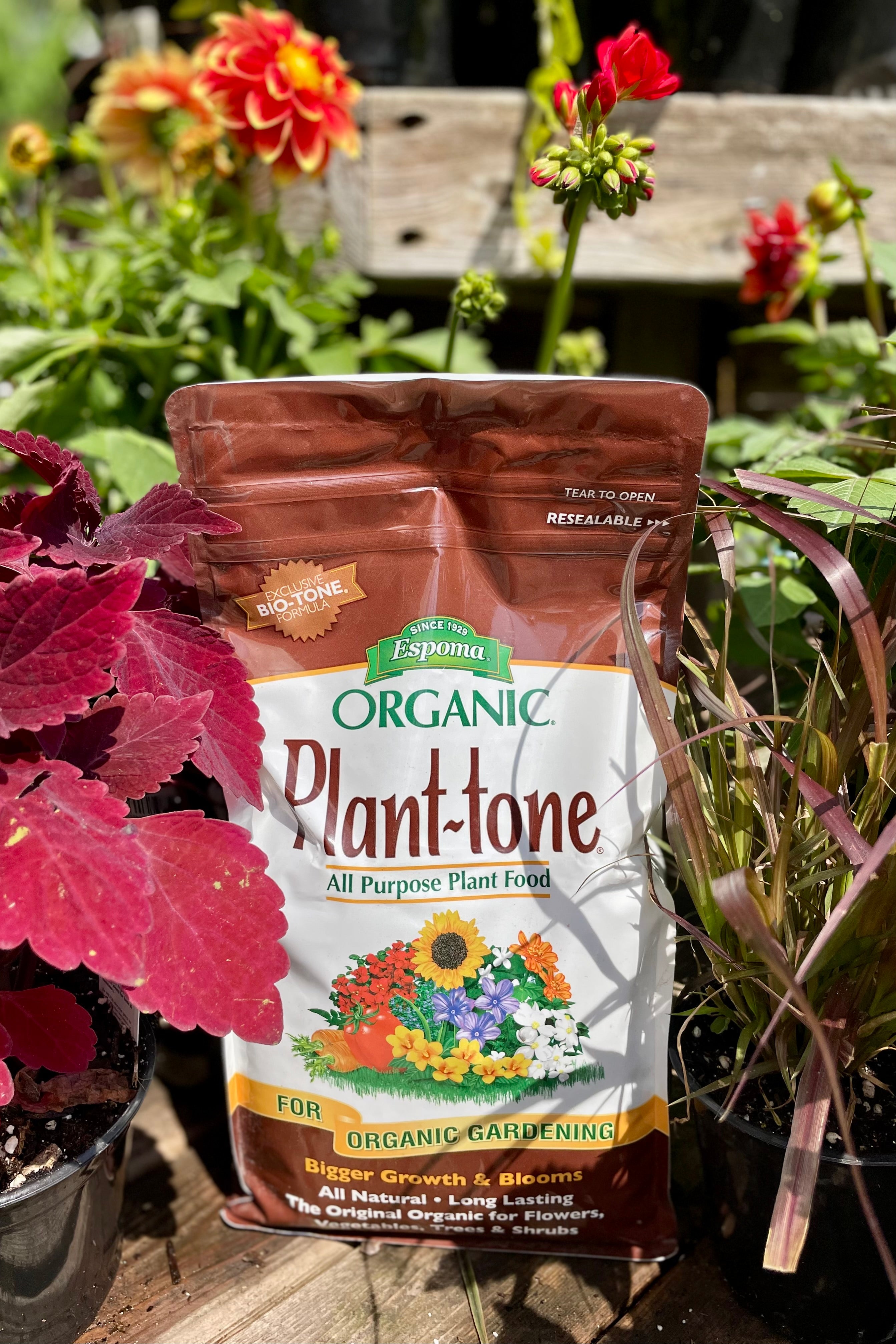 Espoma Organic Plant -Tone 4lb against a lush garden with colorfull flowers and plants
