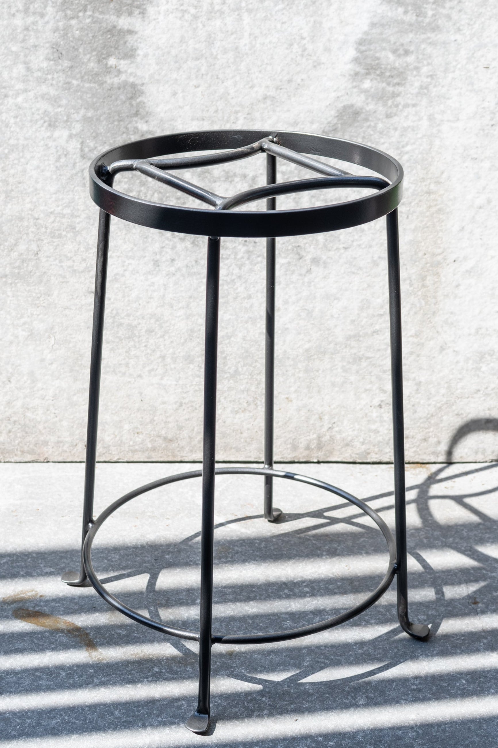 The Large Argyle Plant Stand shown from the side against a grey wall. ©Sprout Home