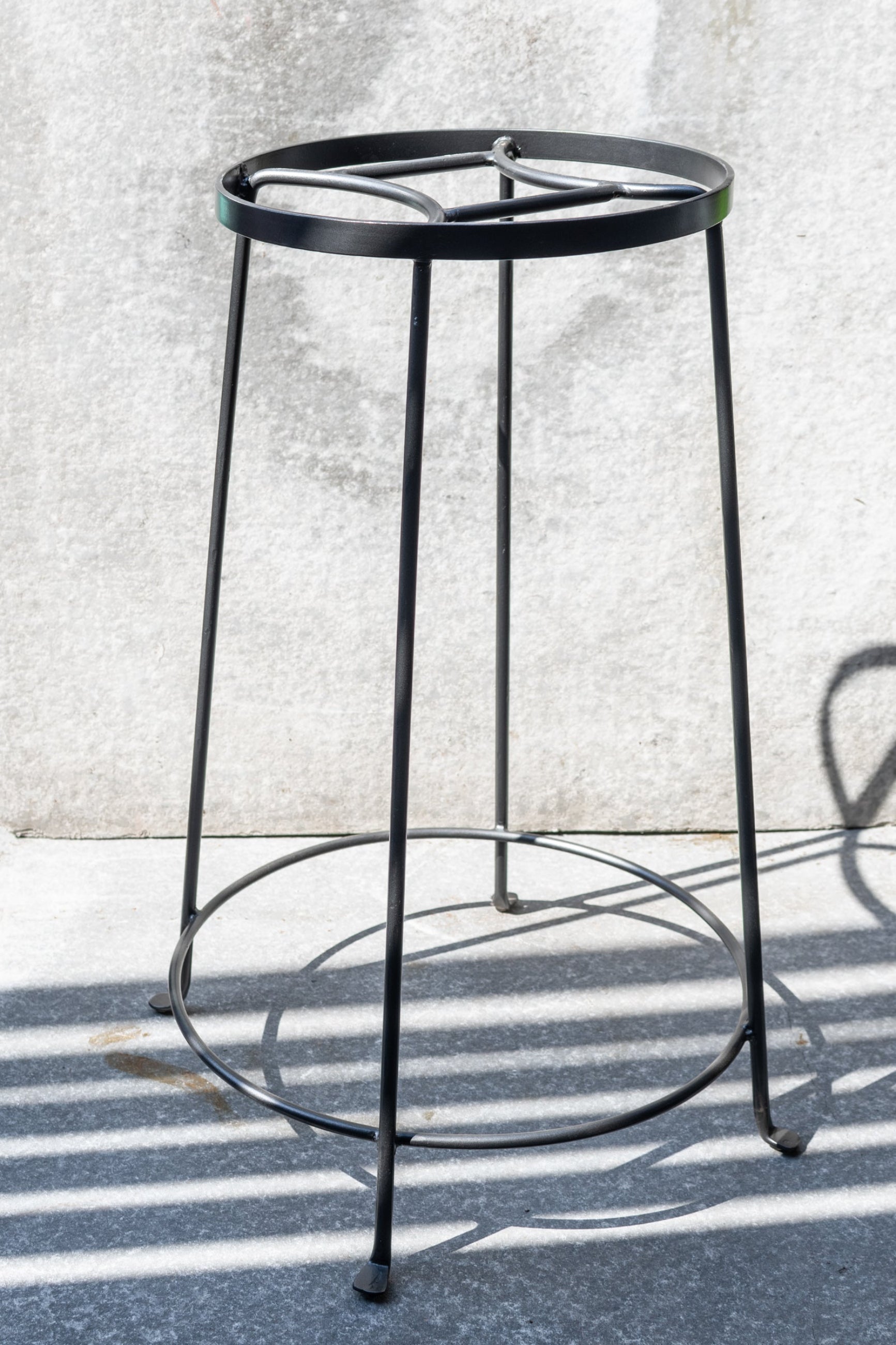 The Extra Large Arglye plant stand shown from the side against a grey wall.