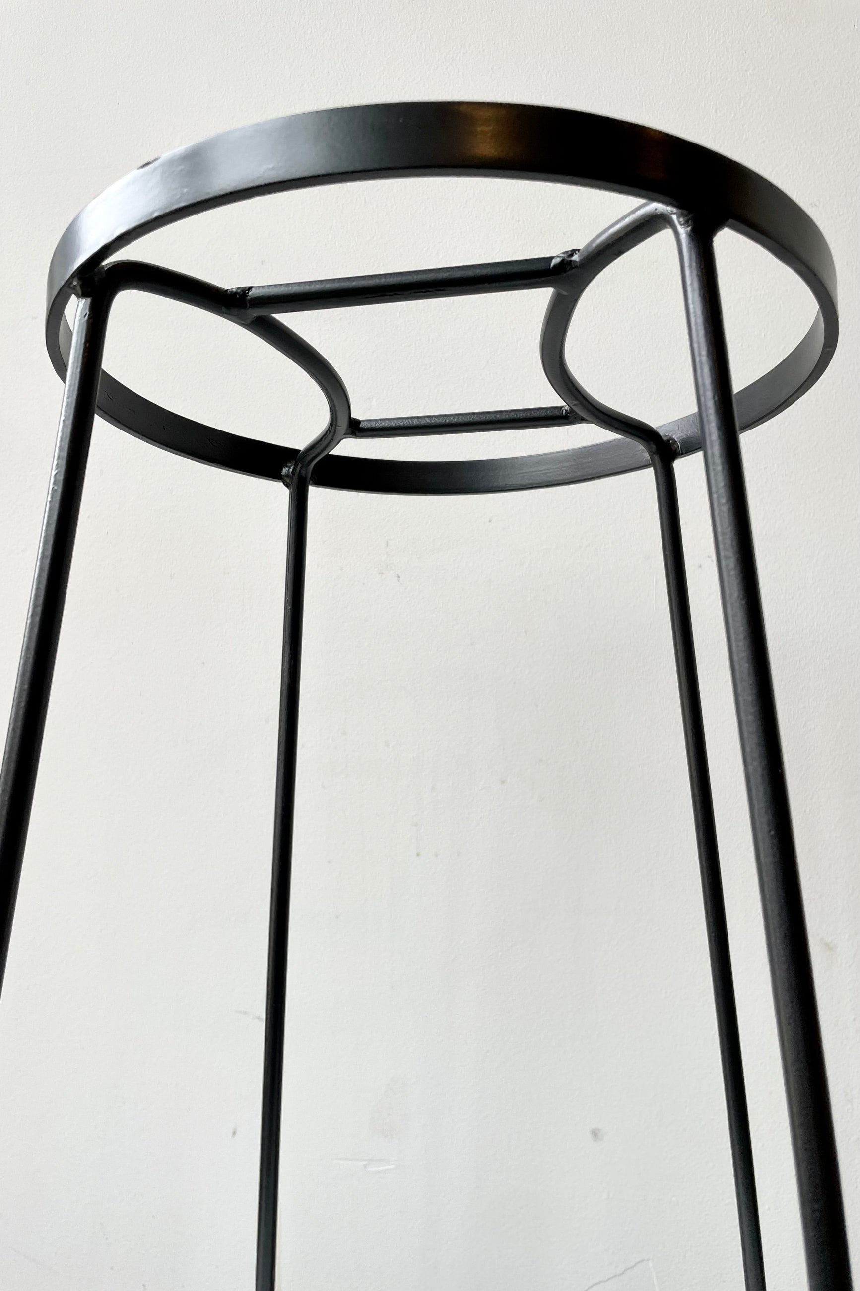 detail of The Extra Large Arglye plant stand shown from the side against a grey wall.