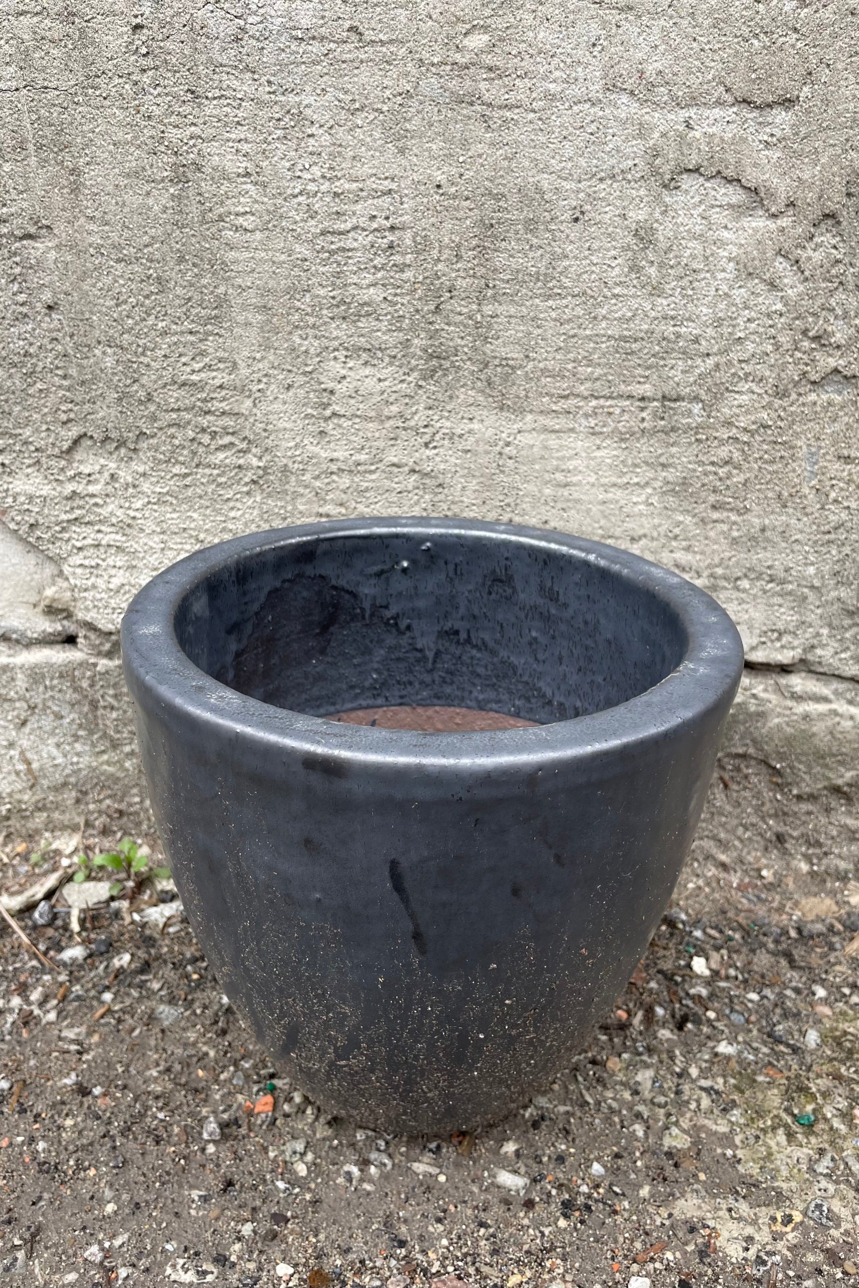 detail of the top of Egg Ceramic Planter Graphite Small against a grey wall ©Sprout Home