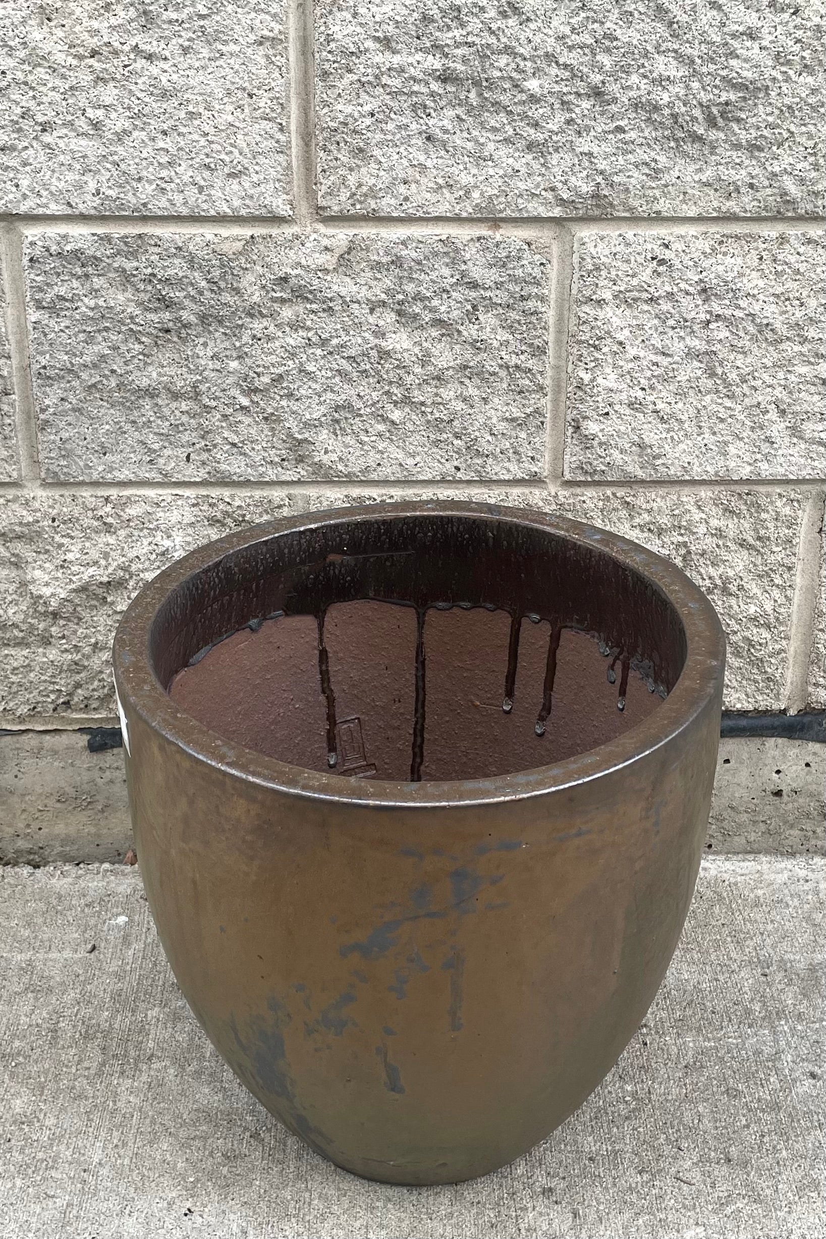 A slightly overhead view of Egg Ceramic Planter Heavy Metal Large against concrete backdrop