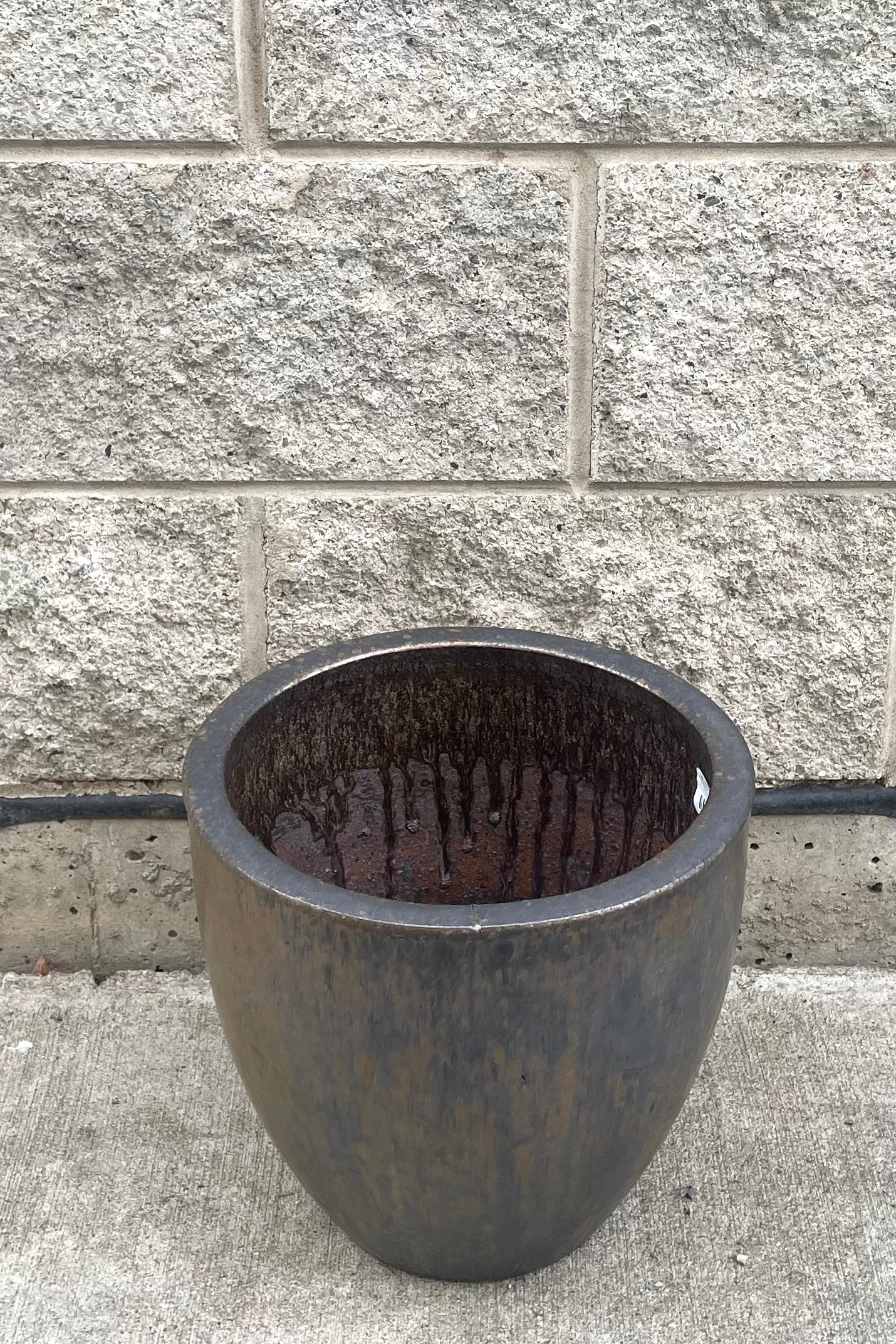 A slight overhead vie of Egg Ceramic Planter Heavy Metal Medium against concrete backdrop