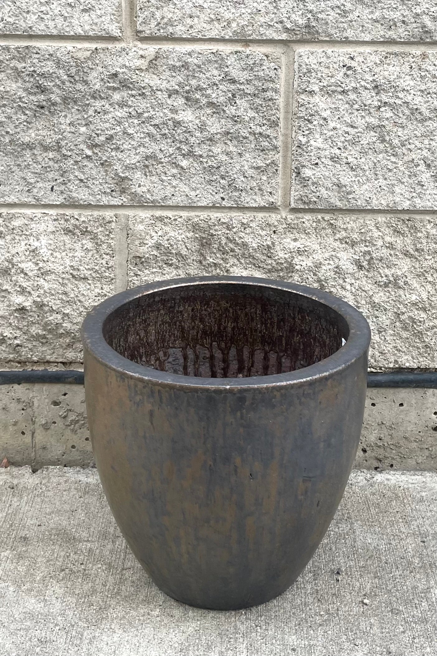 A full frontal view of Egg Ceramic Planter Heavy Metal Medium against concrete backdrop