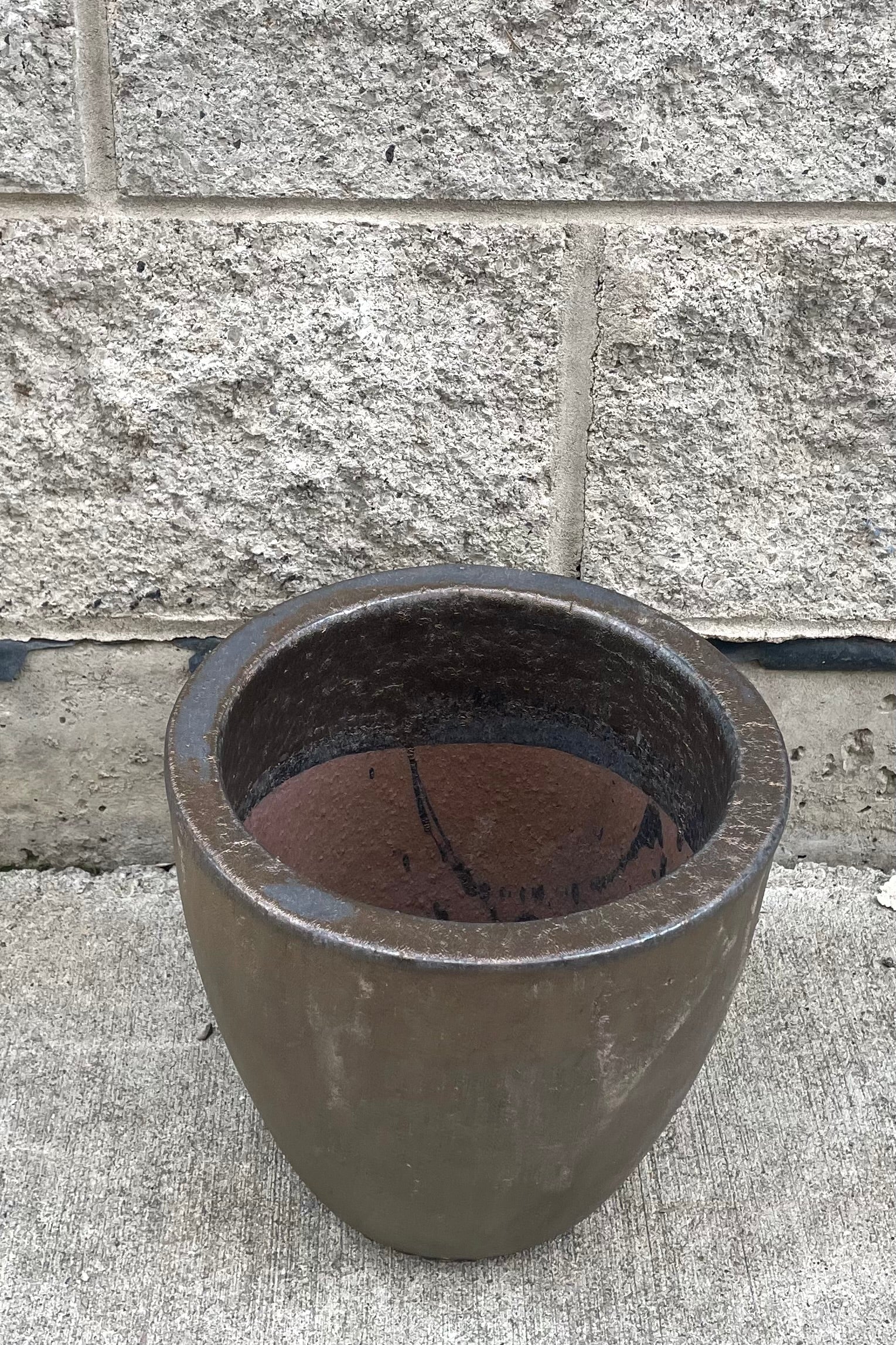 A slight overhead vie of Egg Ceramic Planter Heavy Metal Small against concrete backdrop