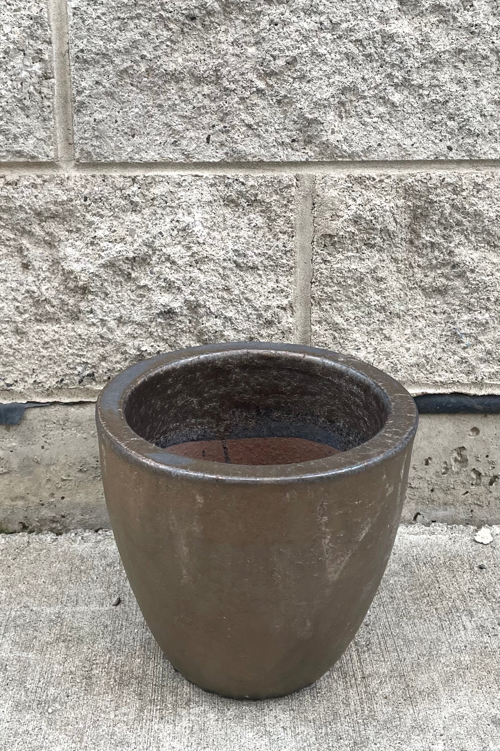 A full frontal view of Egg Ceramic Planter Heavy Metal Small against concrete backdrop