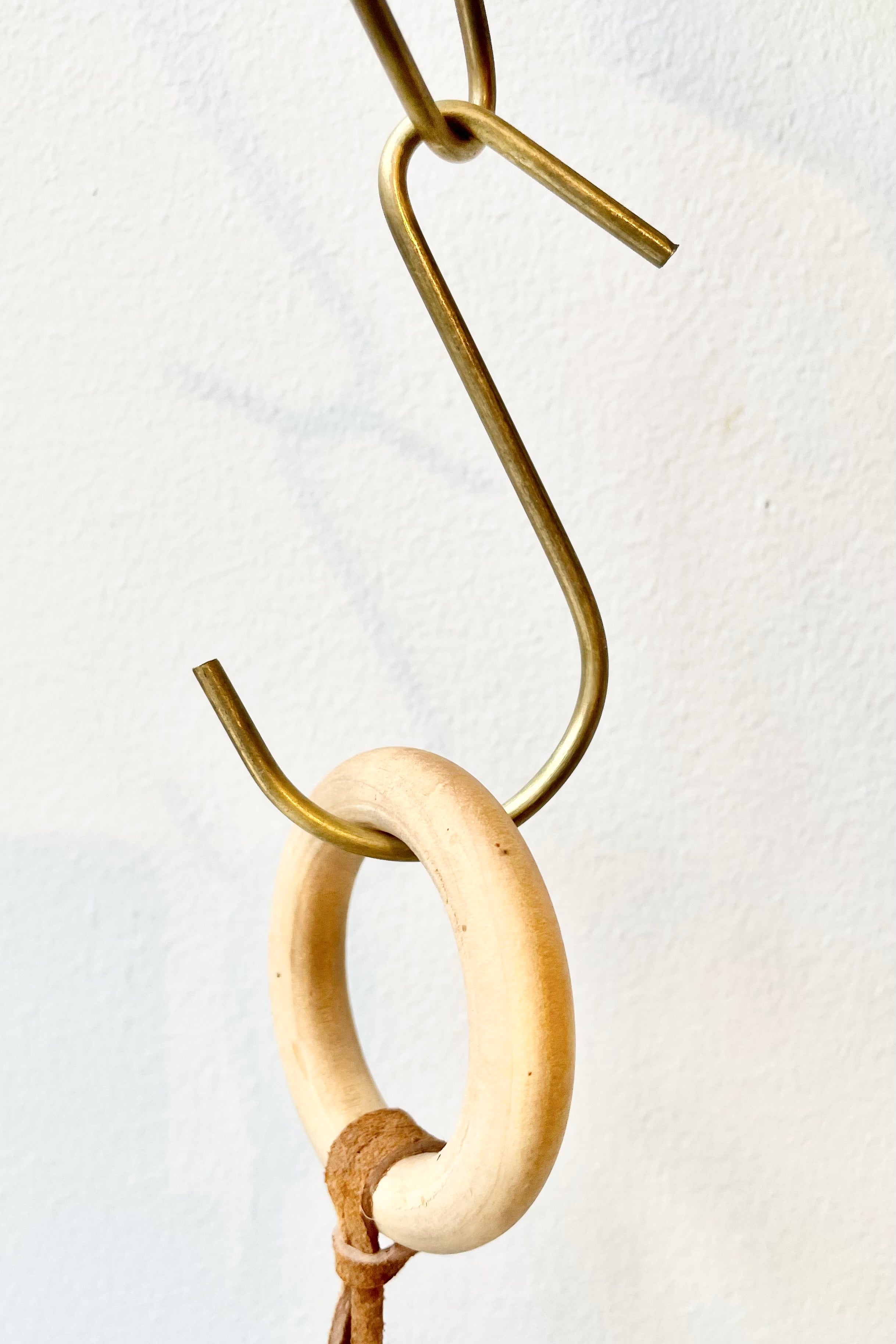 detail of Small brass hook by Fog Linen in front of white background