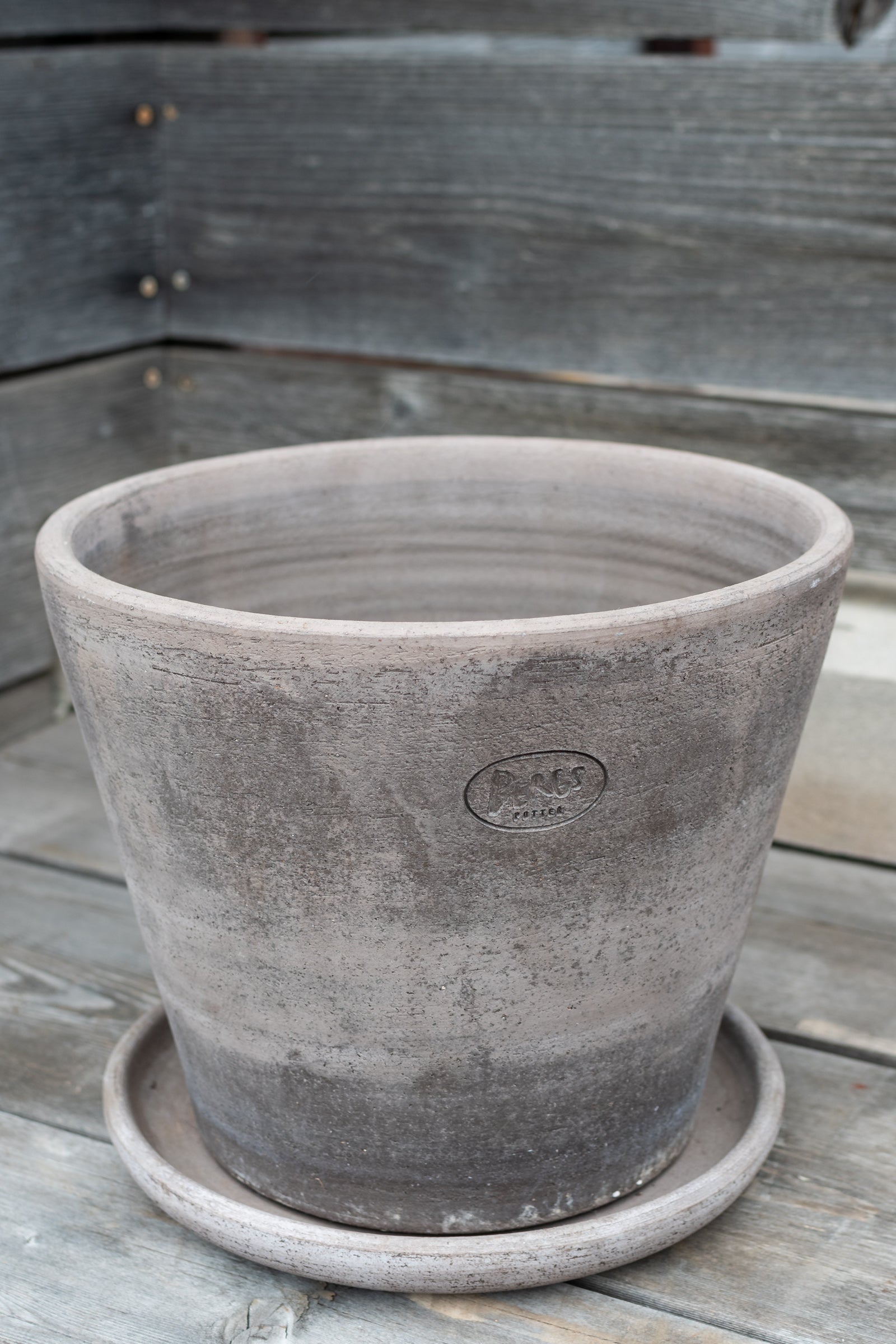 Julie pot by Bergs Potter in a gray color, empty and against a wood fence. ©Sprout Home
