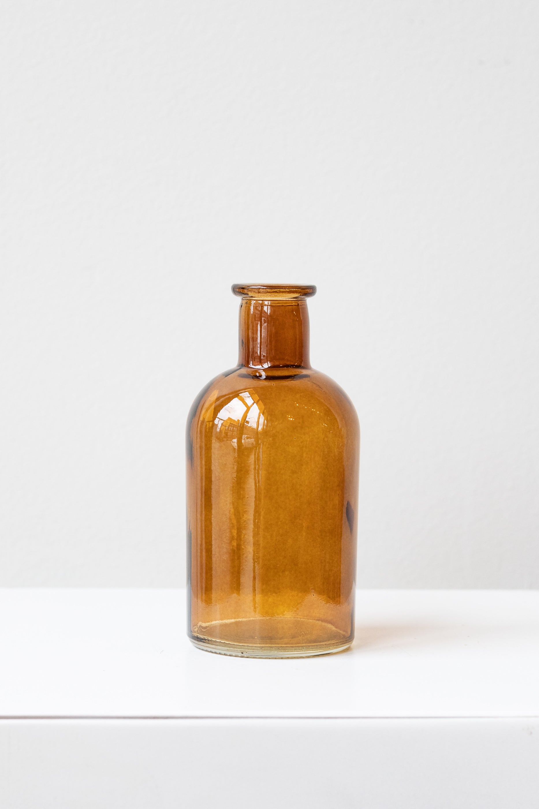 Amber medicine glass bud vase in front of white background