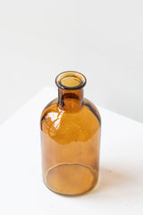 Amber medicine glass bud vase in front of white background