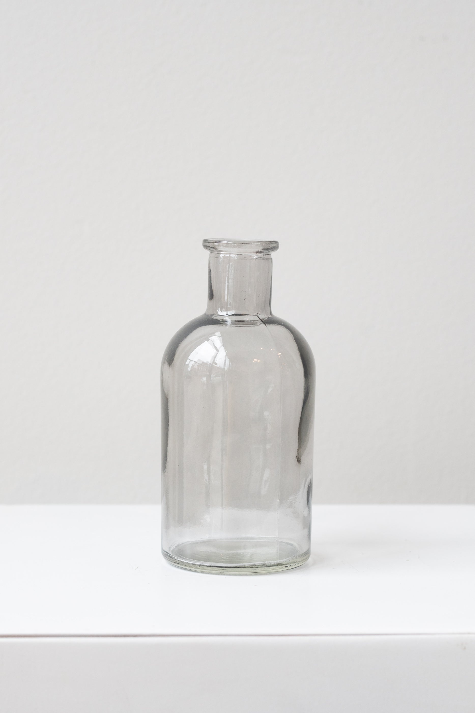 Grey medicine glass bud vase in front of white background