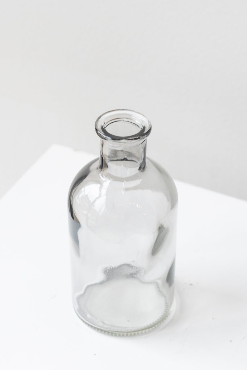 Grey medicine glass bud vase in front of white background