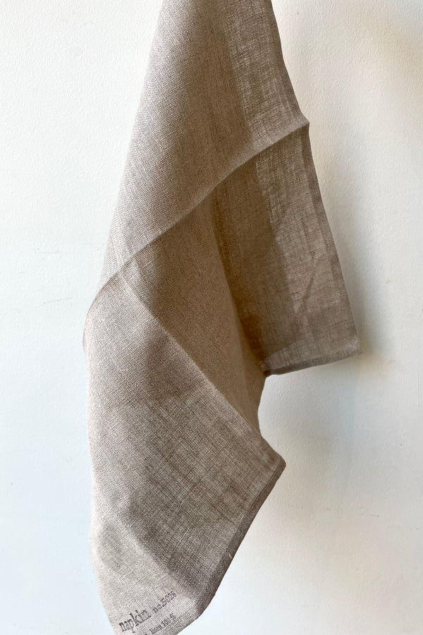 The natural linen napkin is unfolded against a white background