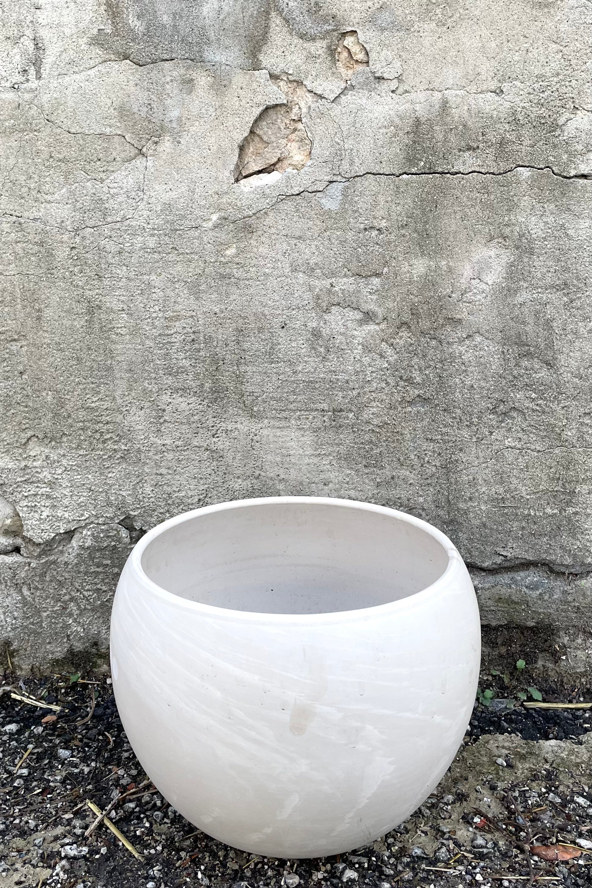A full frontal view of Luna Sphere Pot granite 10" against concrete backdrop