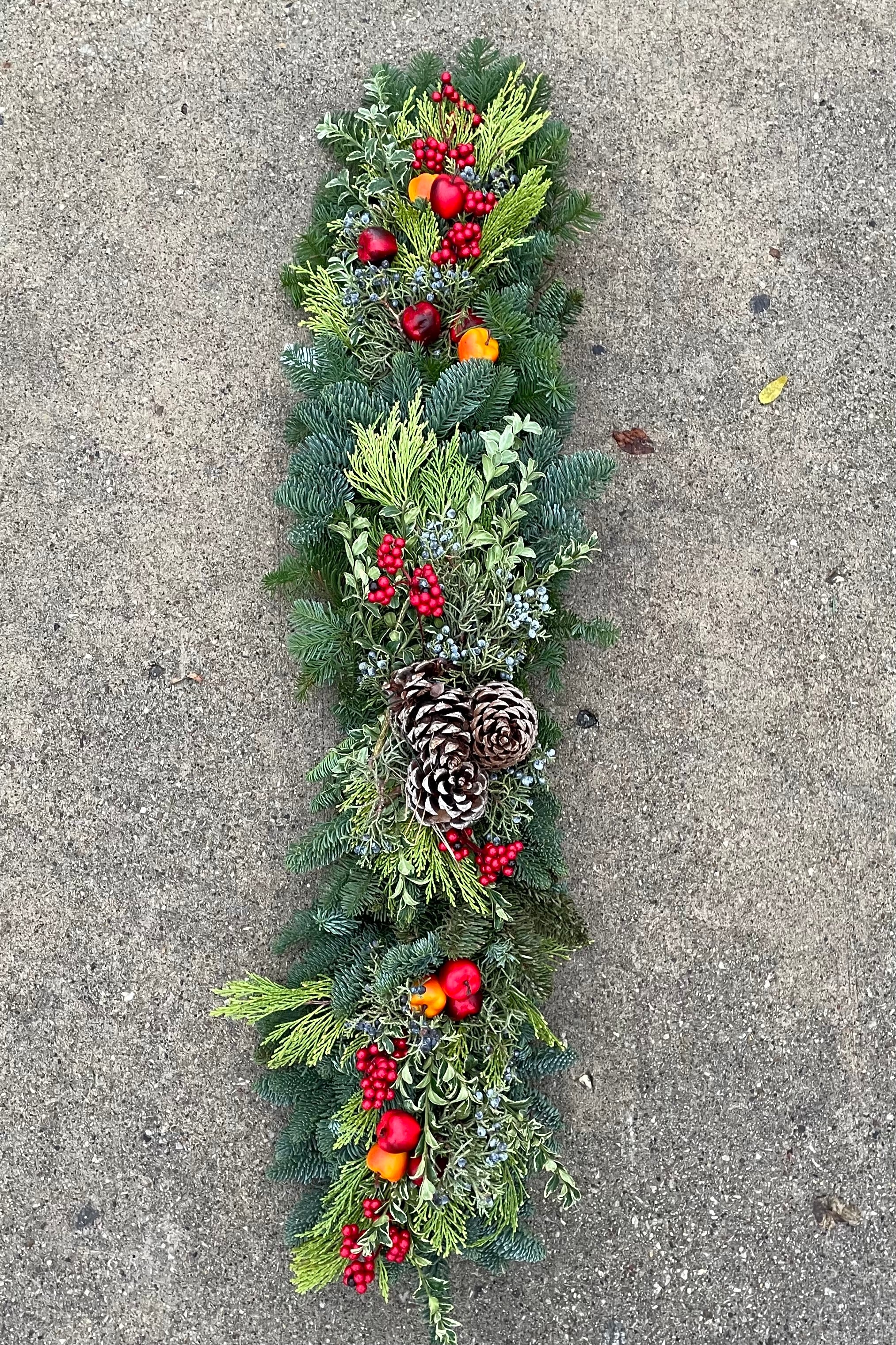 Mantle / Shelf swag piece looking from above it made of evergreen material and faux fruit.