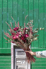Nightcap preserved dried floral arrangement by Sprout Home held in front of bright green painted wall with graffitied ATM