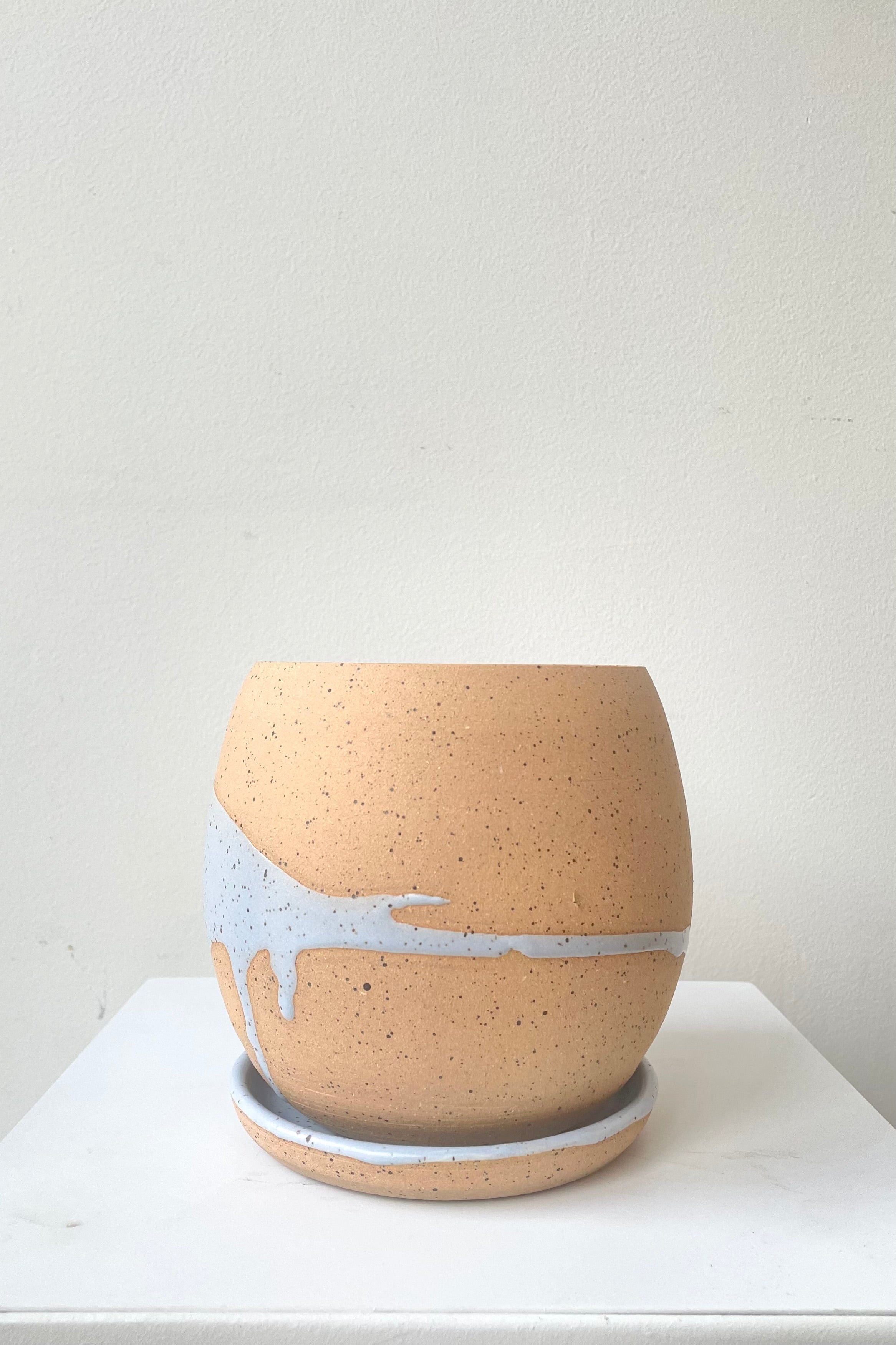 A frontal view of the 4.5" orb pot and saucer in blue against a white backdrop