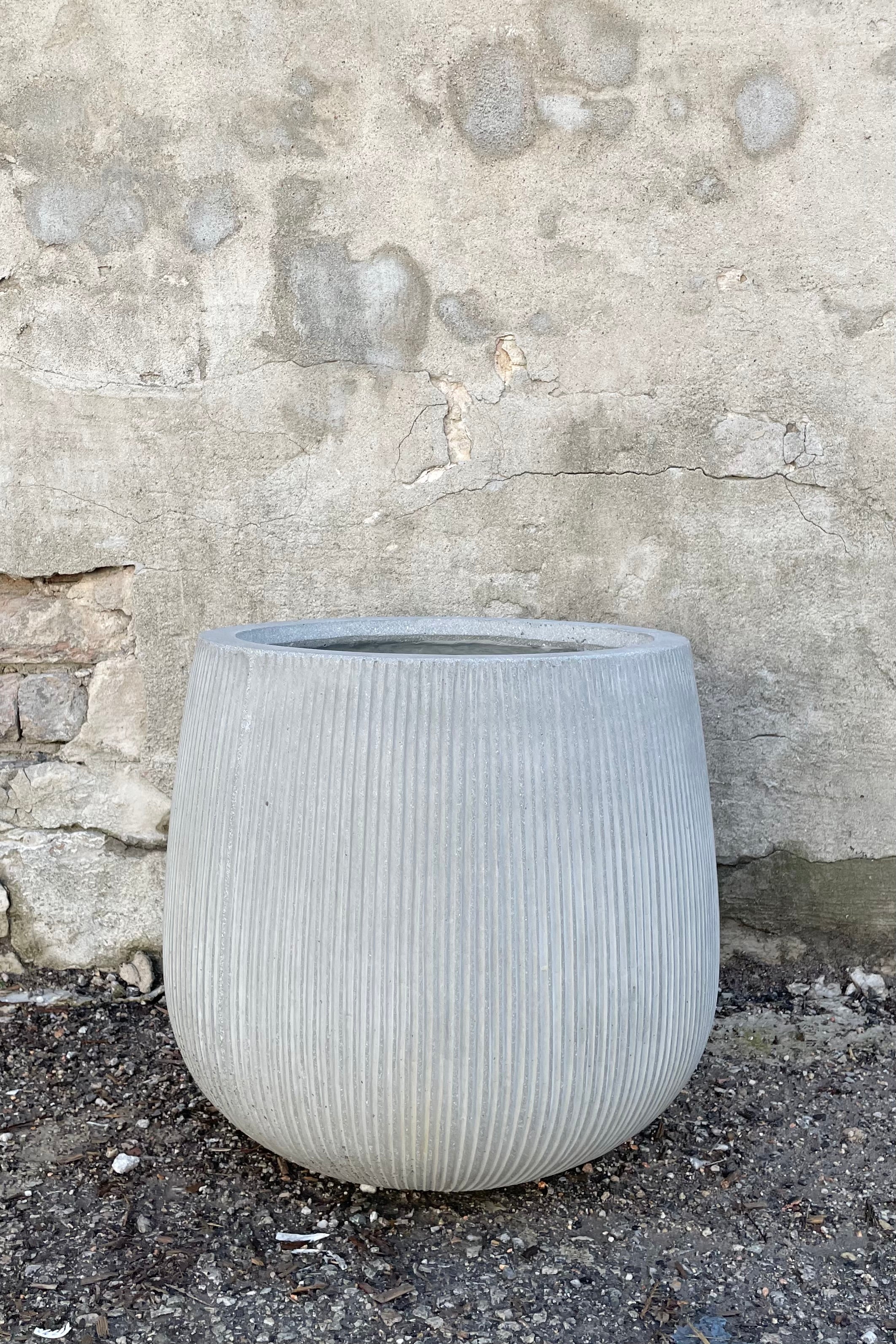 The ridged pax pot in light gray against a concrete wall at Sprout Home.