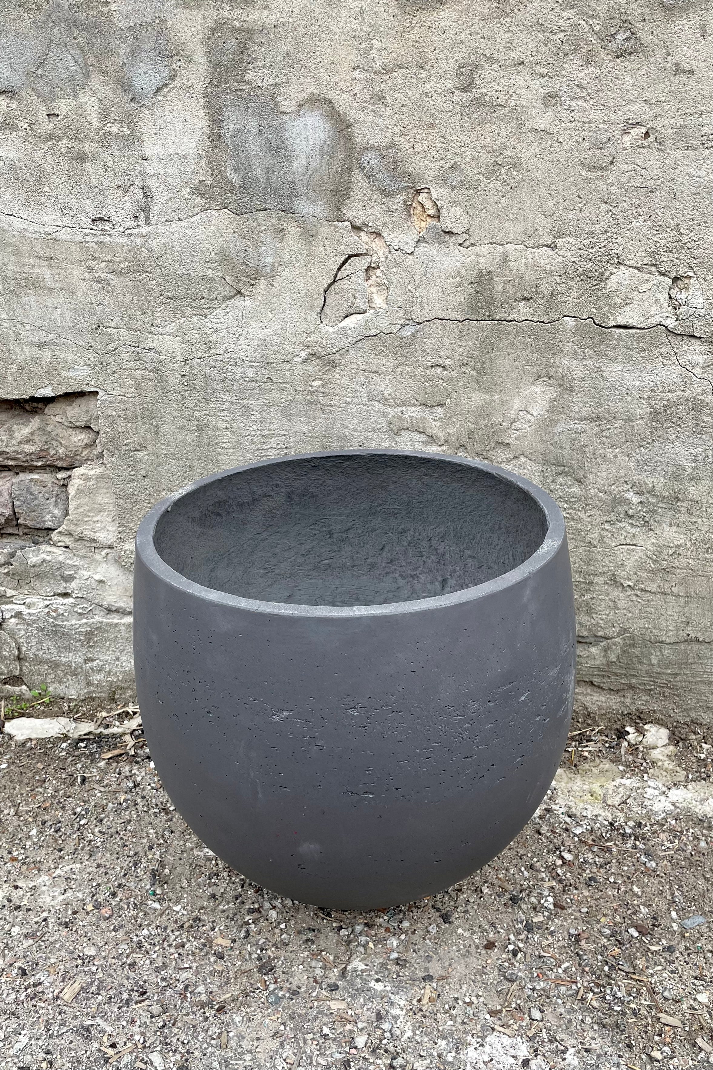 Detail of the top of the Mini Orb Pot Black Washed Extra Large against a grey wall