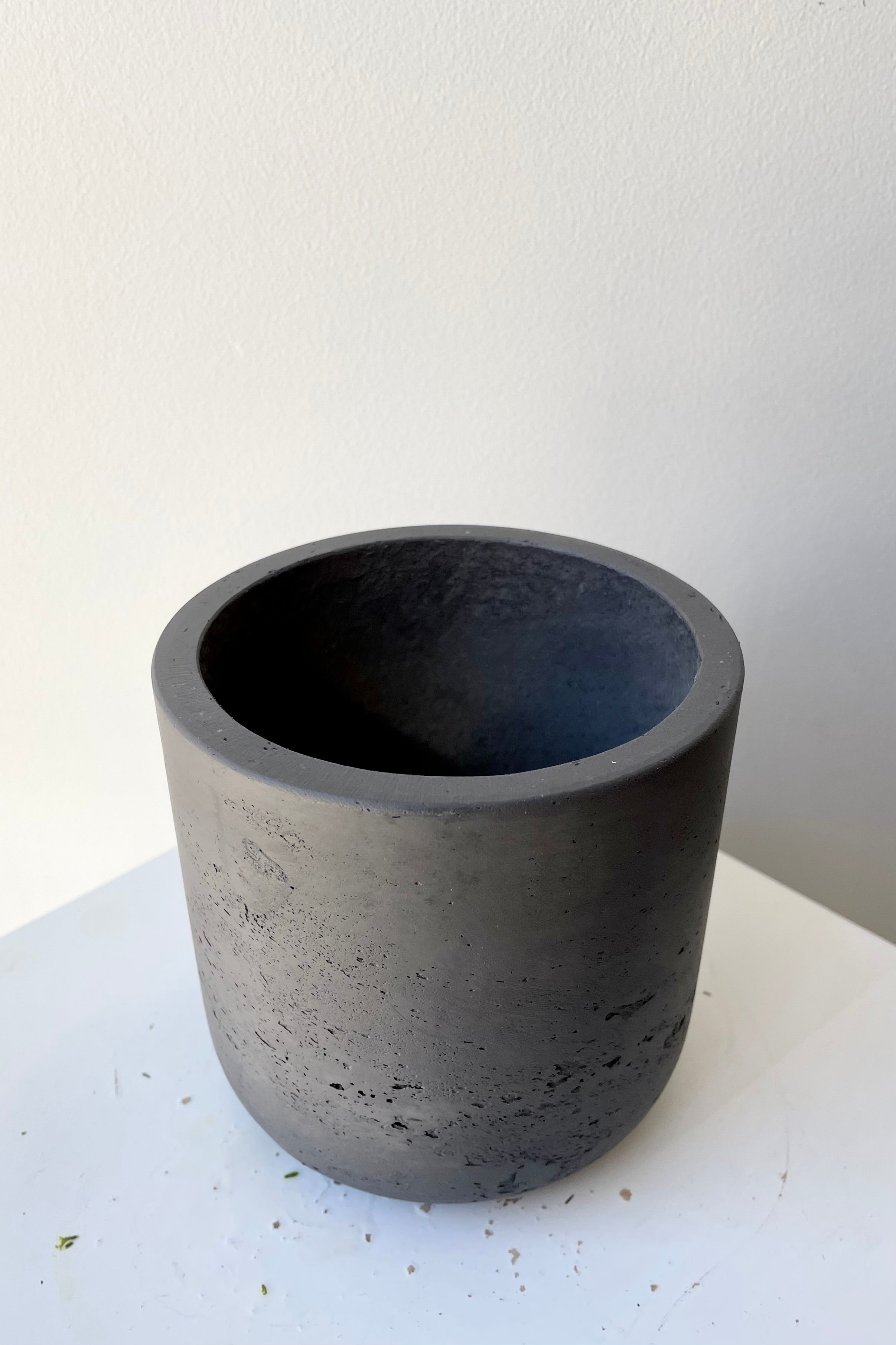 The black washed extra small Charlie pot against a white wall at Sprout Home.